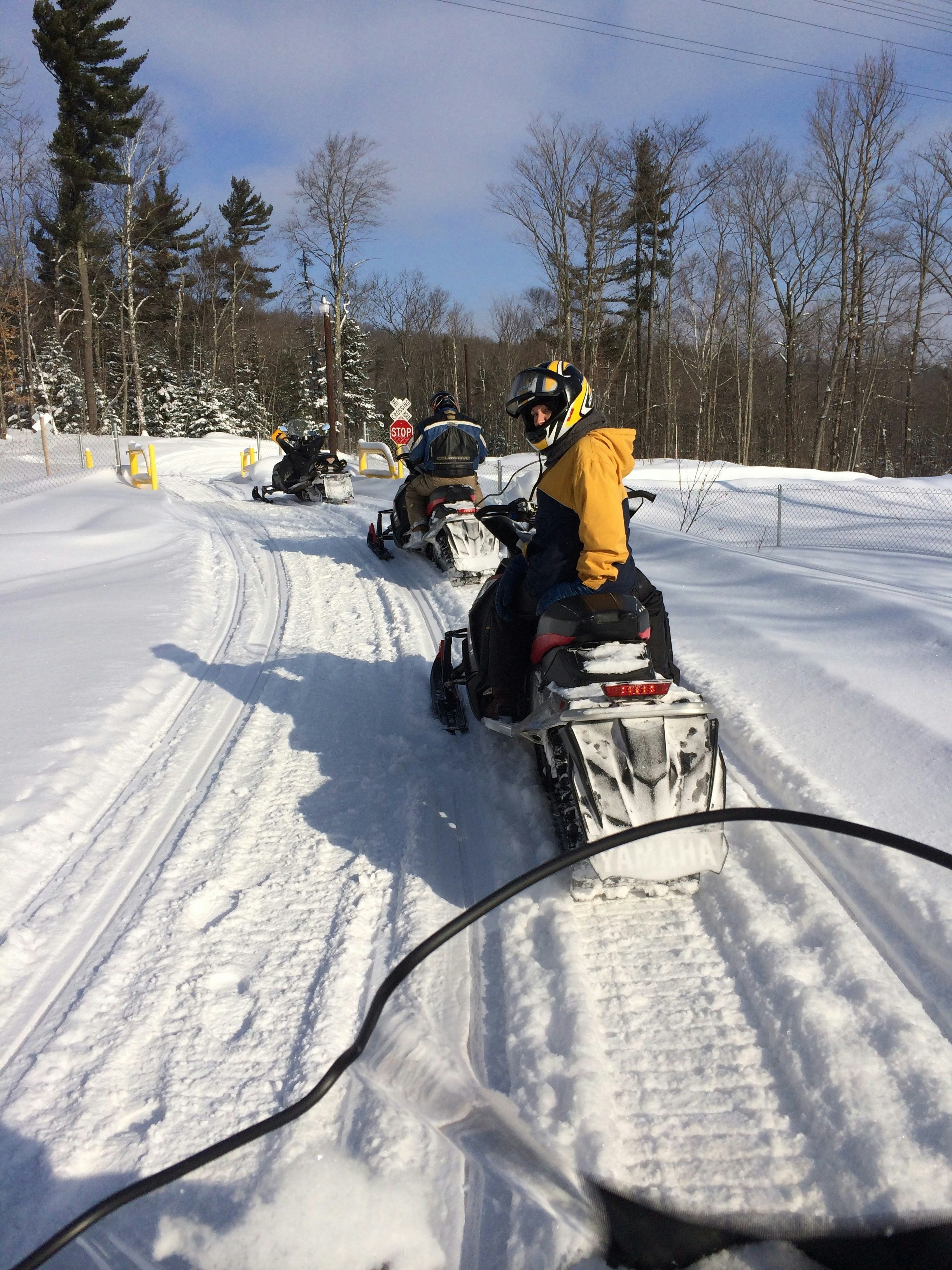 a family on snowmobiles rides through deep snow in a straight line