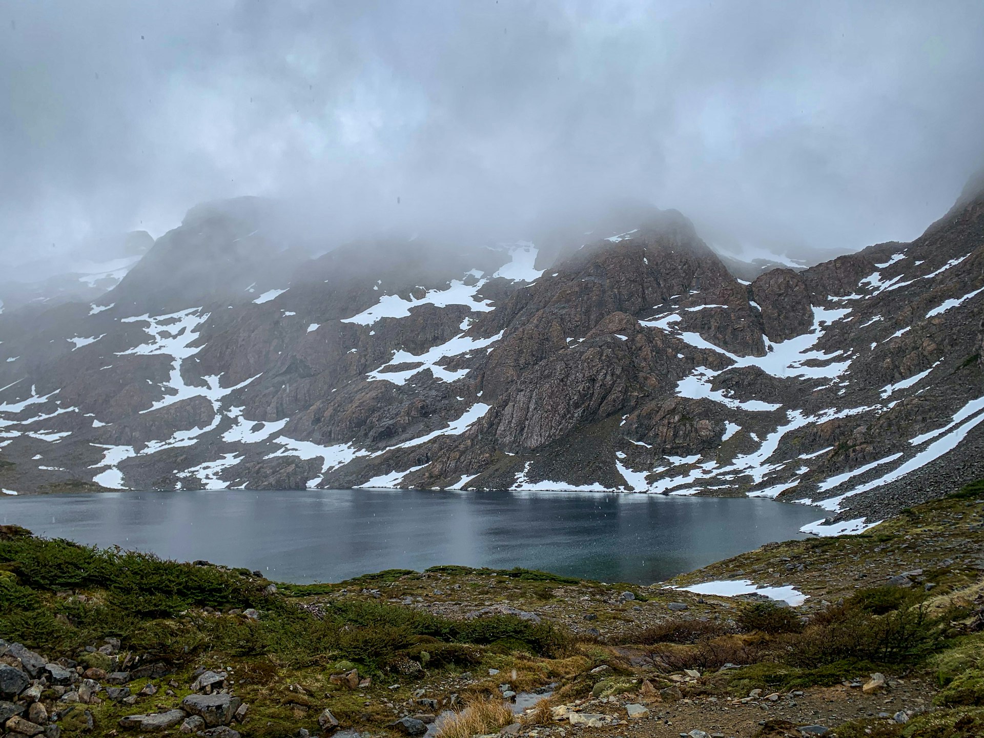 Mist lingers over the top of a snow-dotted peak behind Laguna Escondida.