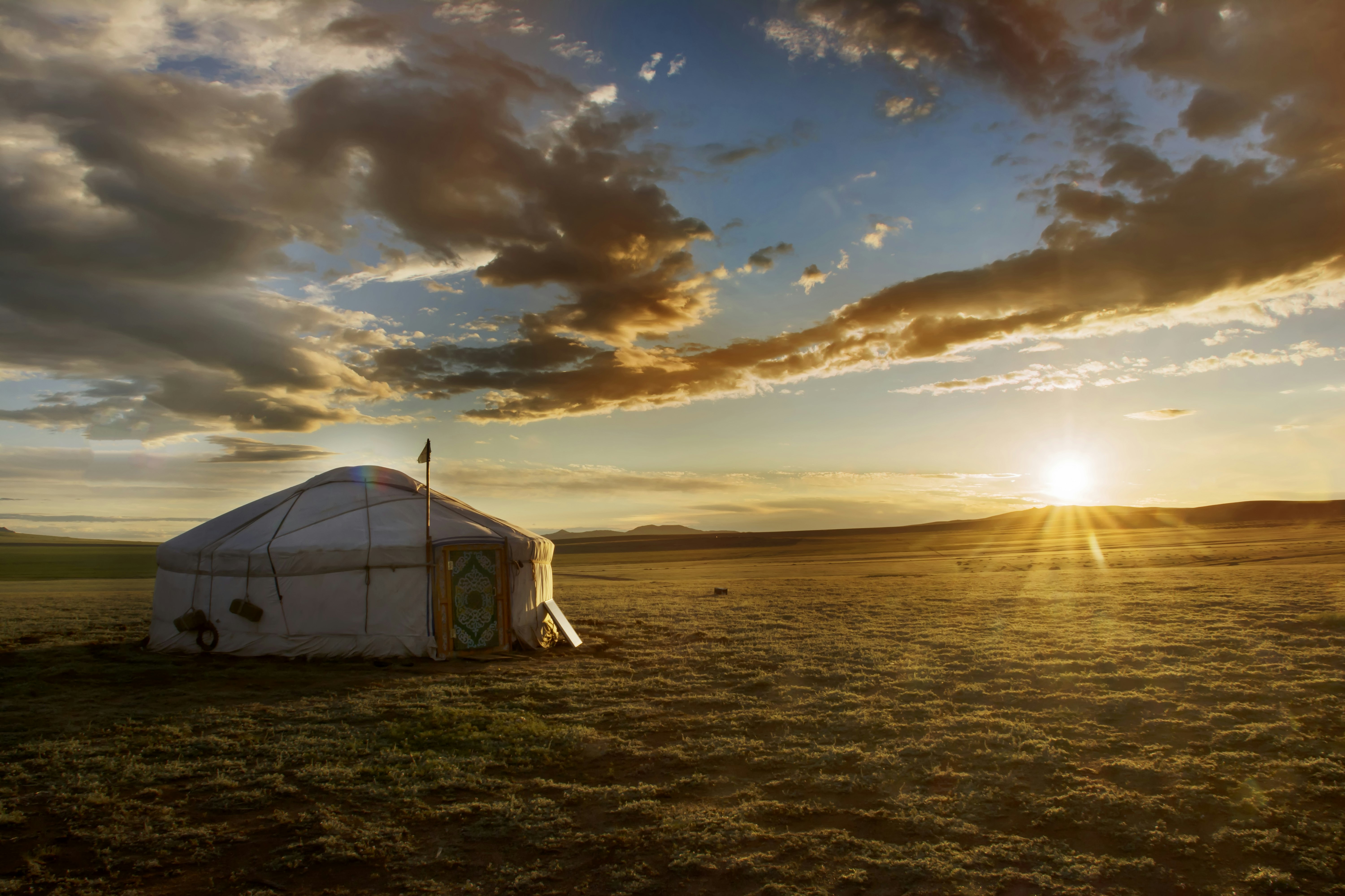 A lone white tent sits in the middle of an open field as the sun rises above the horizon; women adventure travel