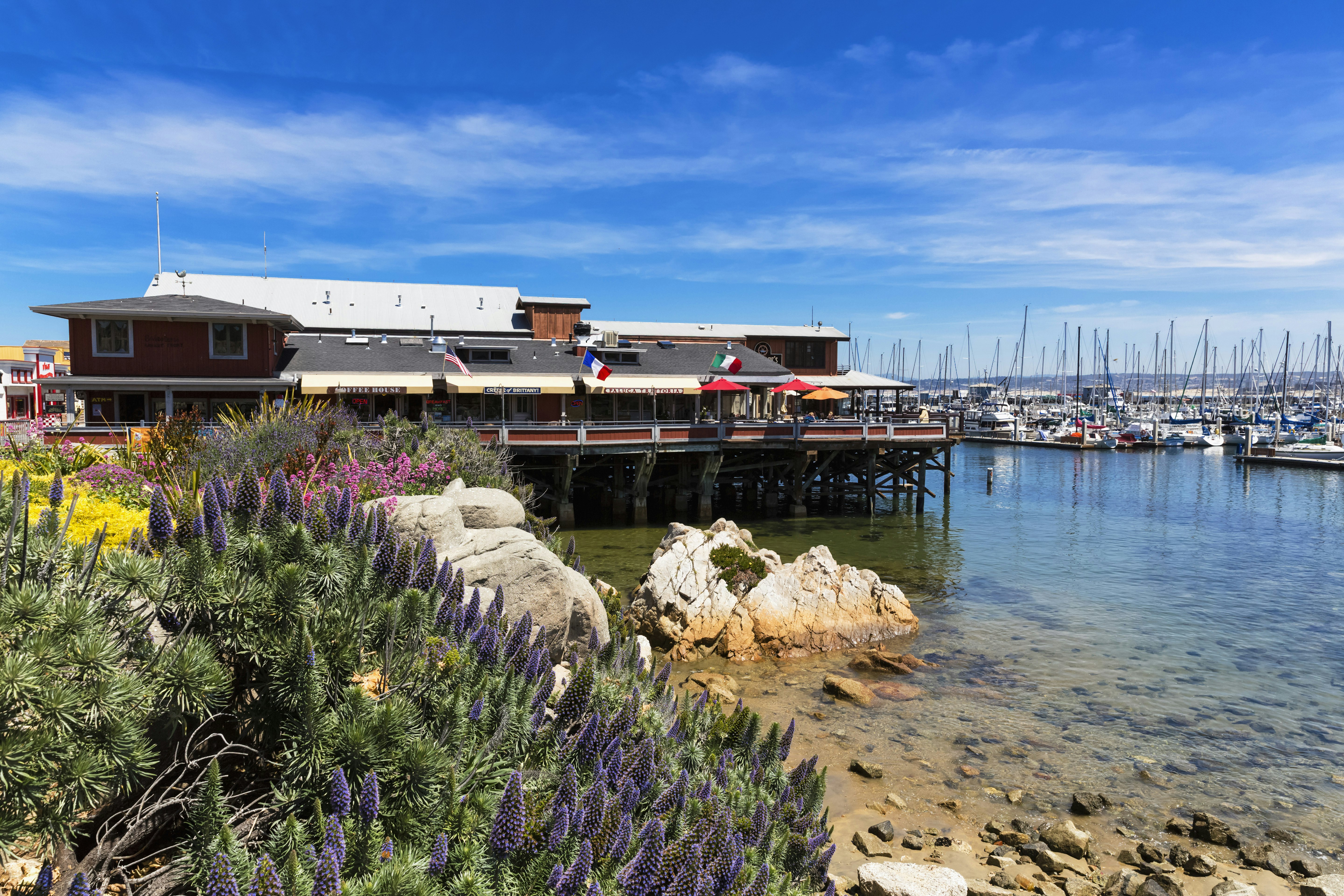 Cannery Wharf in Monterey is seen with a view of several sailboats tied up and the bay stretching out beyond; California ice cream