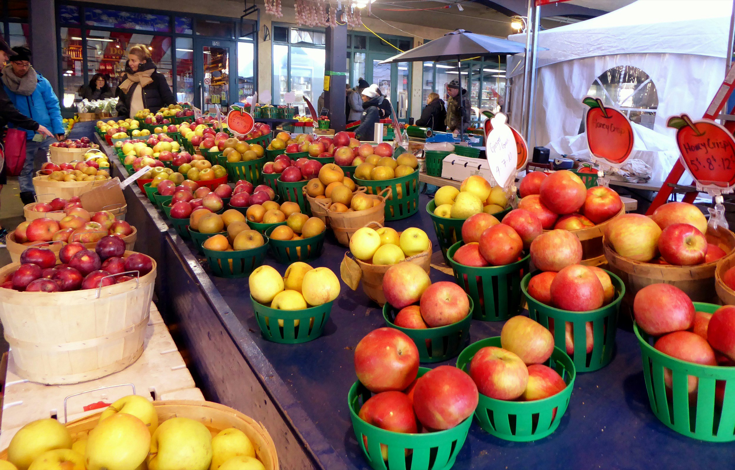 Apples are spread out on a table in a market as people mill about; Fall in Montreal