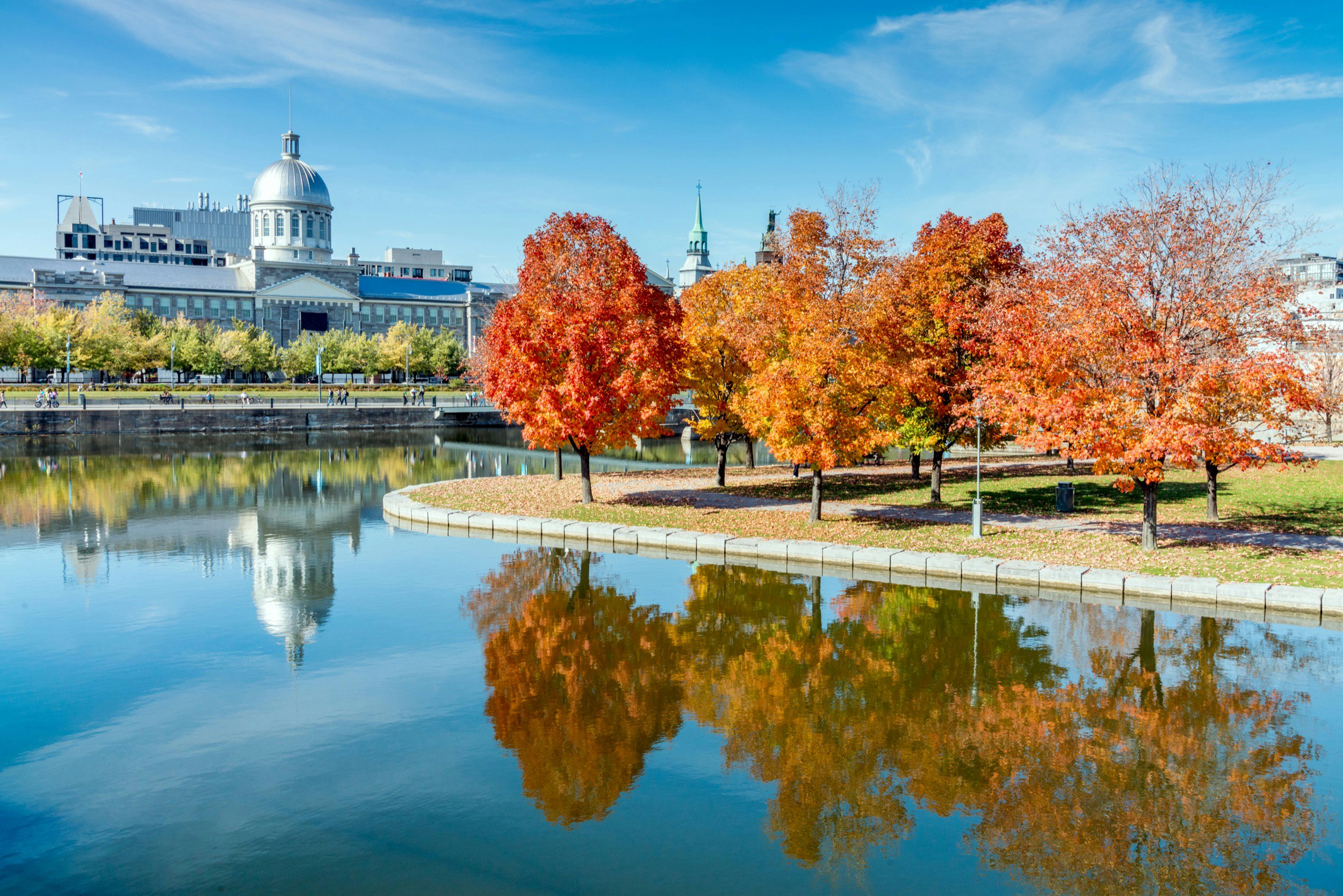 Autumn leaves of red, orange and yellow are reflected in a canal in Montreal, as well as the iconic dome of the market; Fall in Montreal