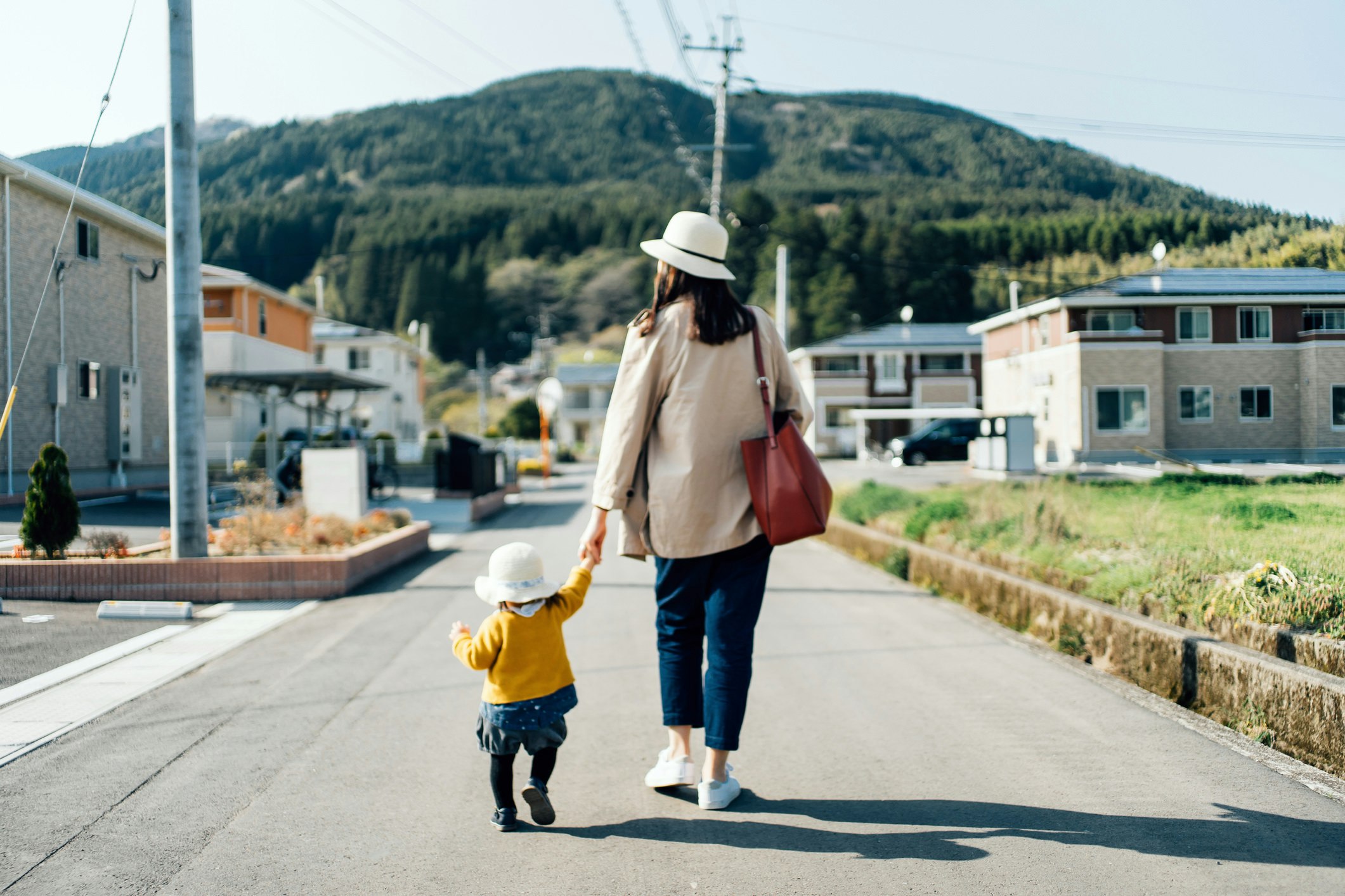 Mother and child, holding hands, walking down the street. 