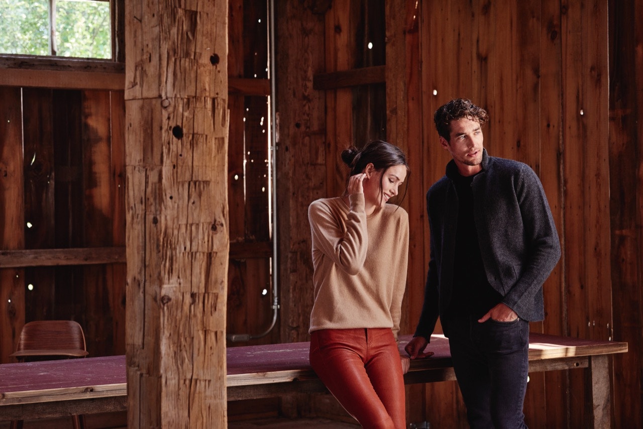 A man and woman in a barn, wearing Naadam's $75 Essential sweater