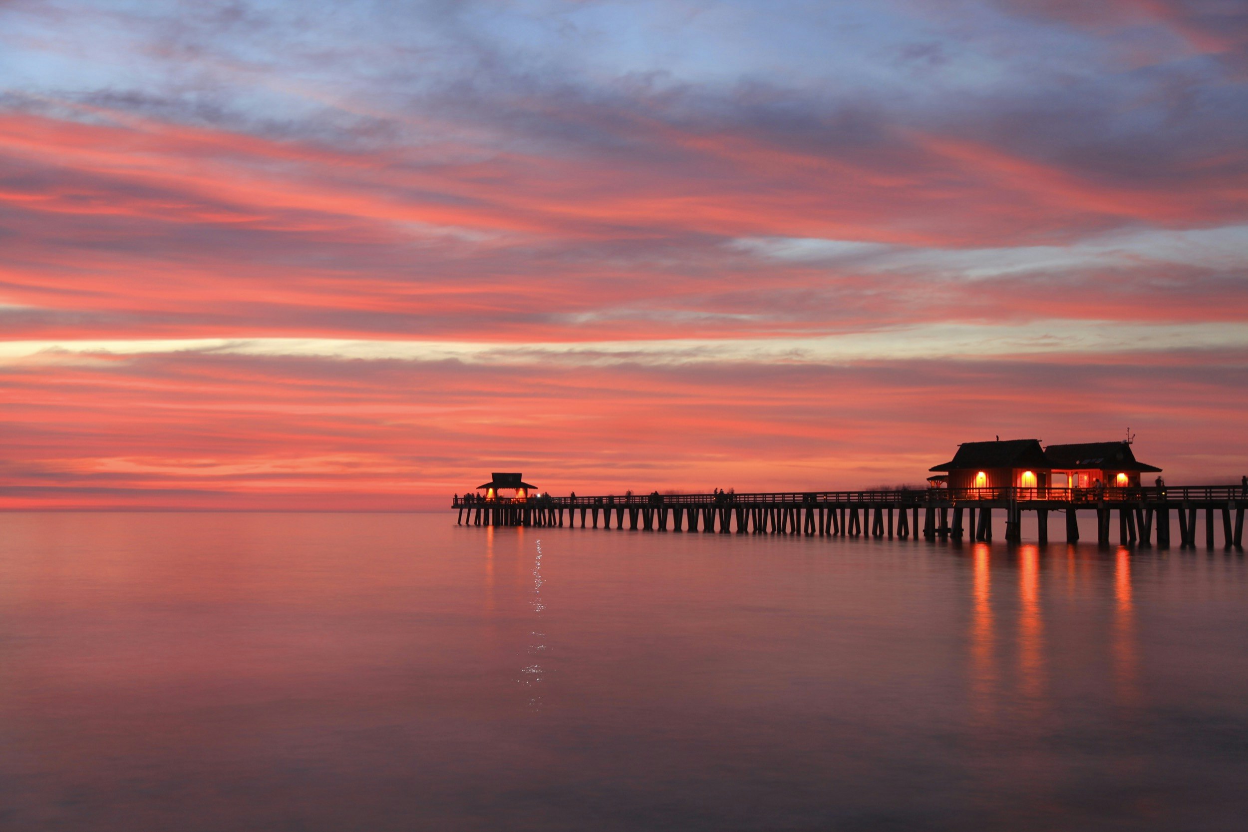 The pier of Naples, Florida is seen at sunset on a calm sea