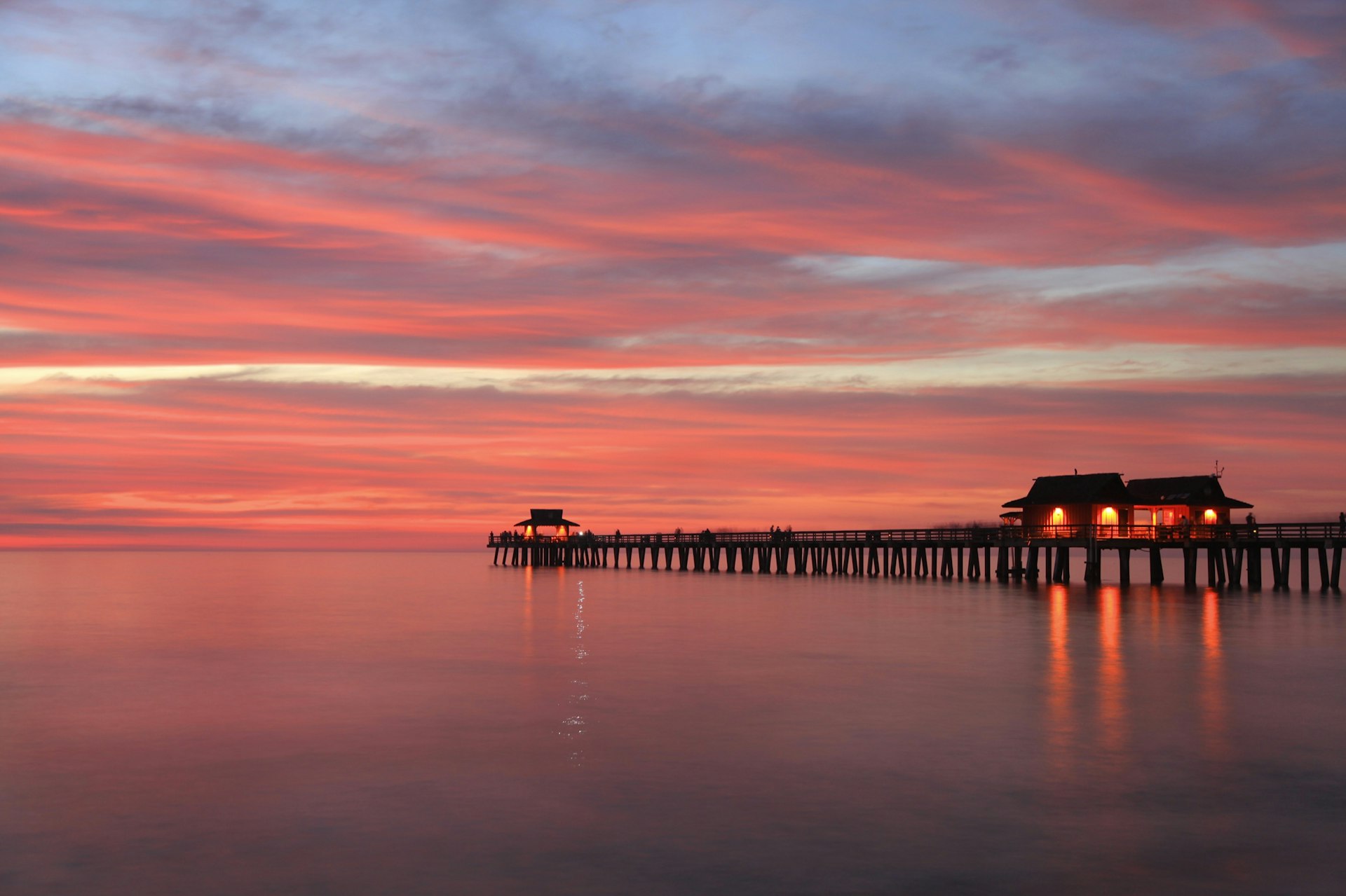 Piren i Naples, Florida ses vid solnedgången på ett lugnt hav
