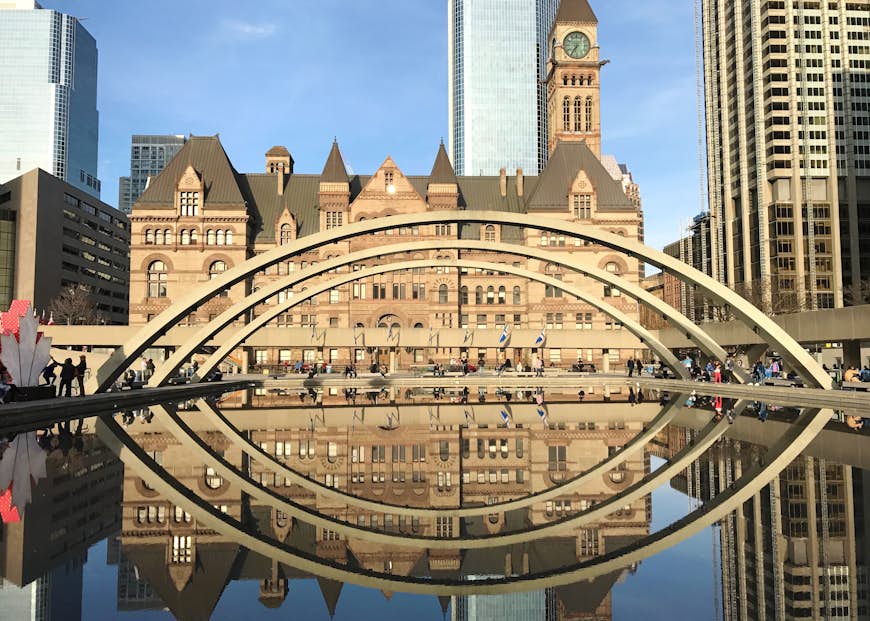 Arches are reflected in a pool below as we look across the water in Nathan Phillips Square in Toronto; Free things to do in Toronto