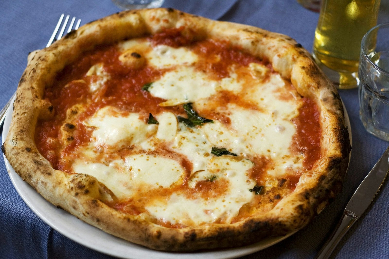 An authentic Neapolitan Pizza Margherita served on a blue woven tablecloth. 