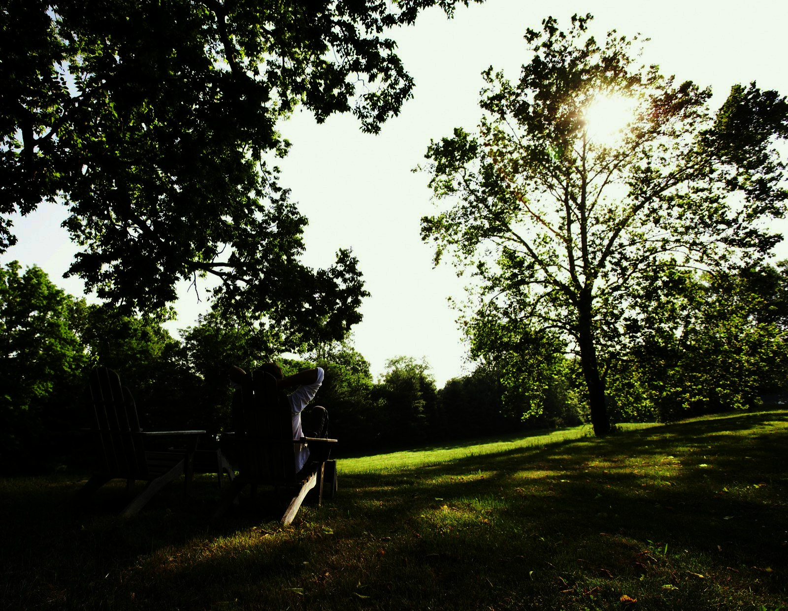 A man relaxes in a wooden chair on a grassy lawn in New Hope, Pennsylvania