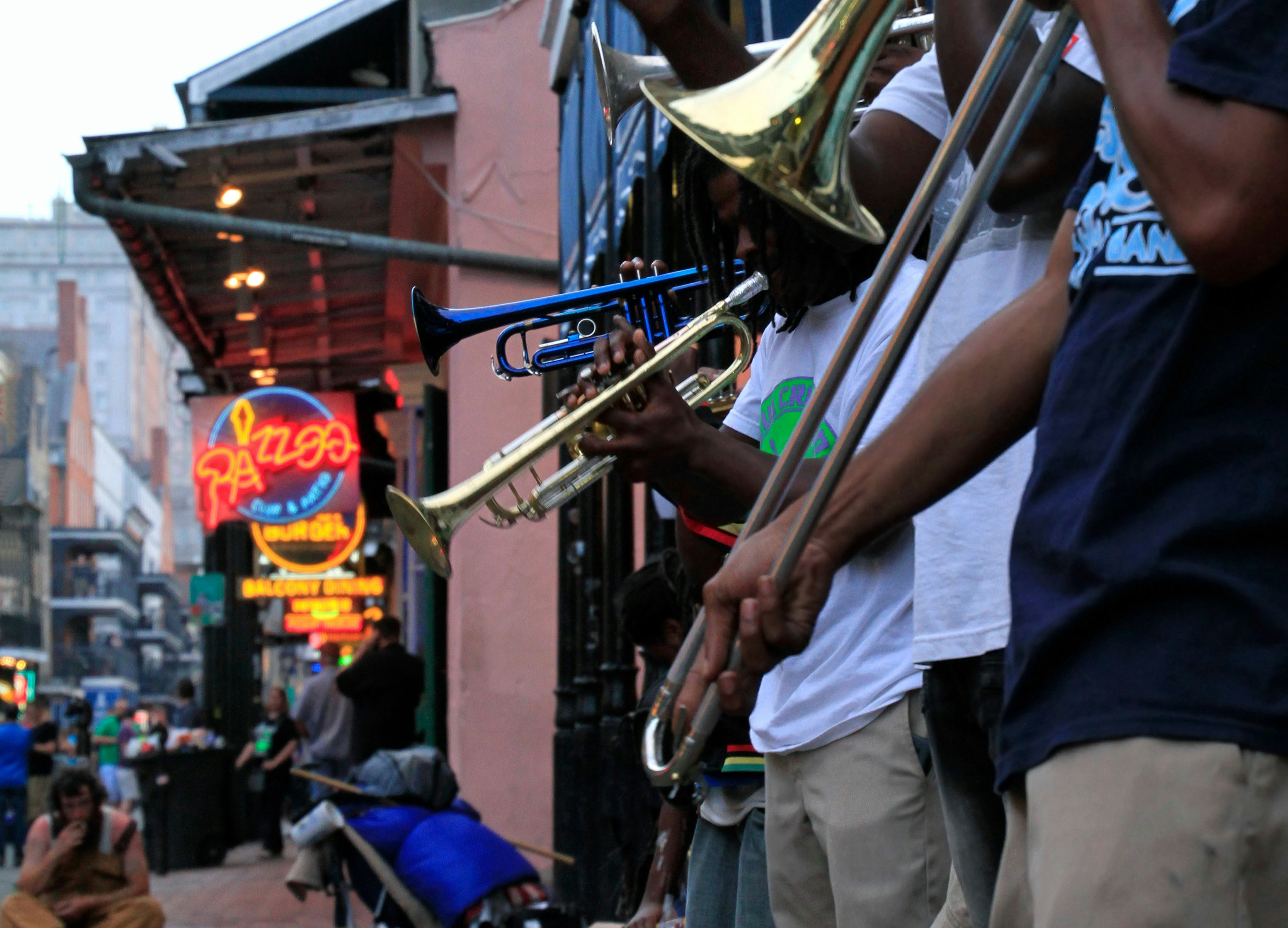 Jazz musicians performing in the French Quarter of New Orleans, with crowds and neon lights in the background.