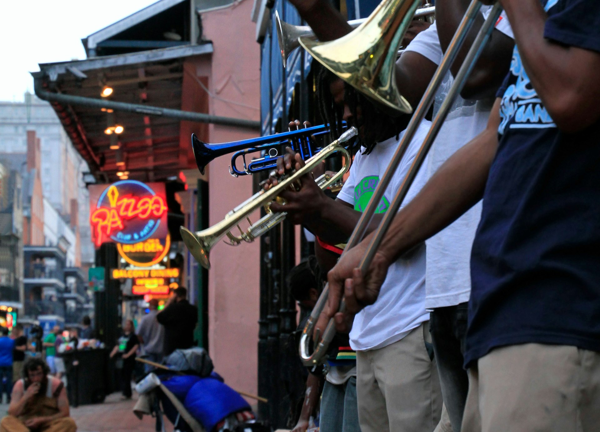Jazzmusiker uppträder i det franska kvarteret i New Orleans, med folkmassor och neonljus i bakgrunden.