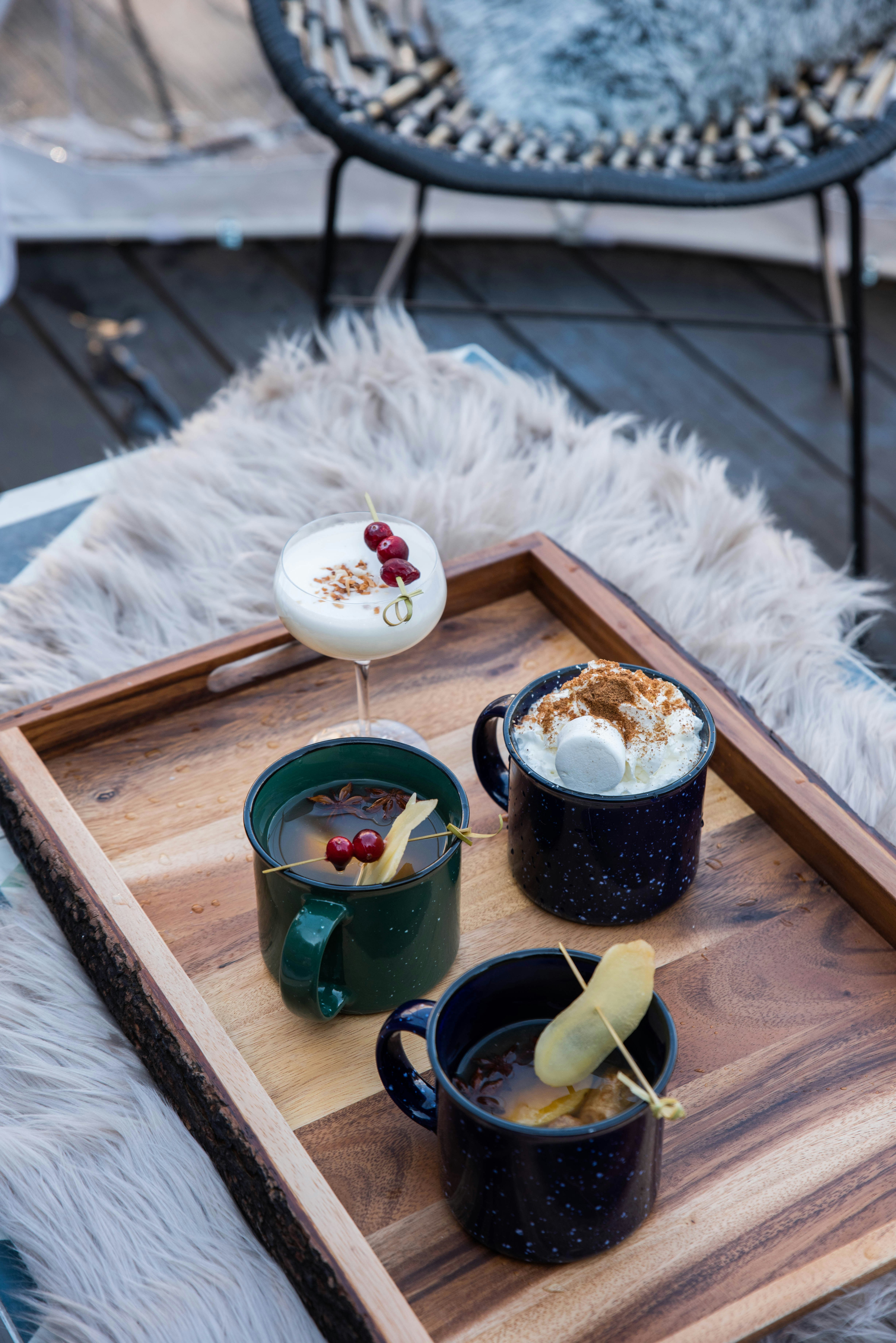 A selection of drinks, including mugs of hot punch and hot chocolate, are laid out on a rustic wooden tray at the Nordic Village at Bobby Hotel, Nashville.