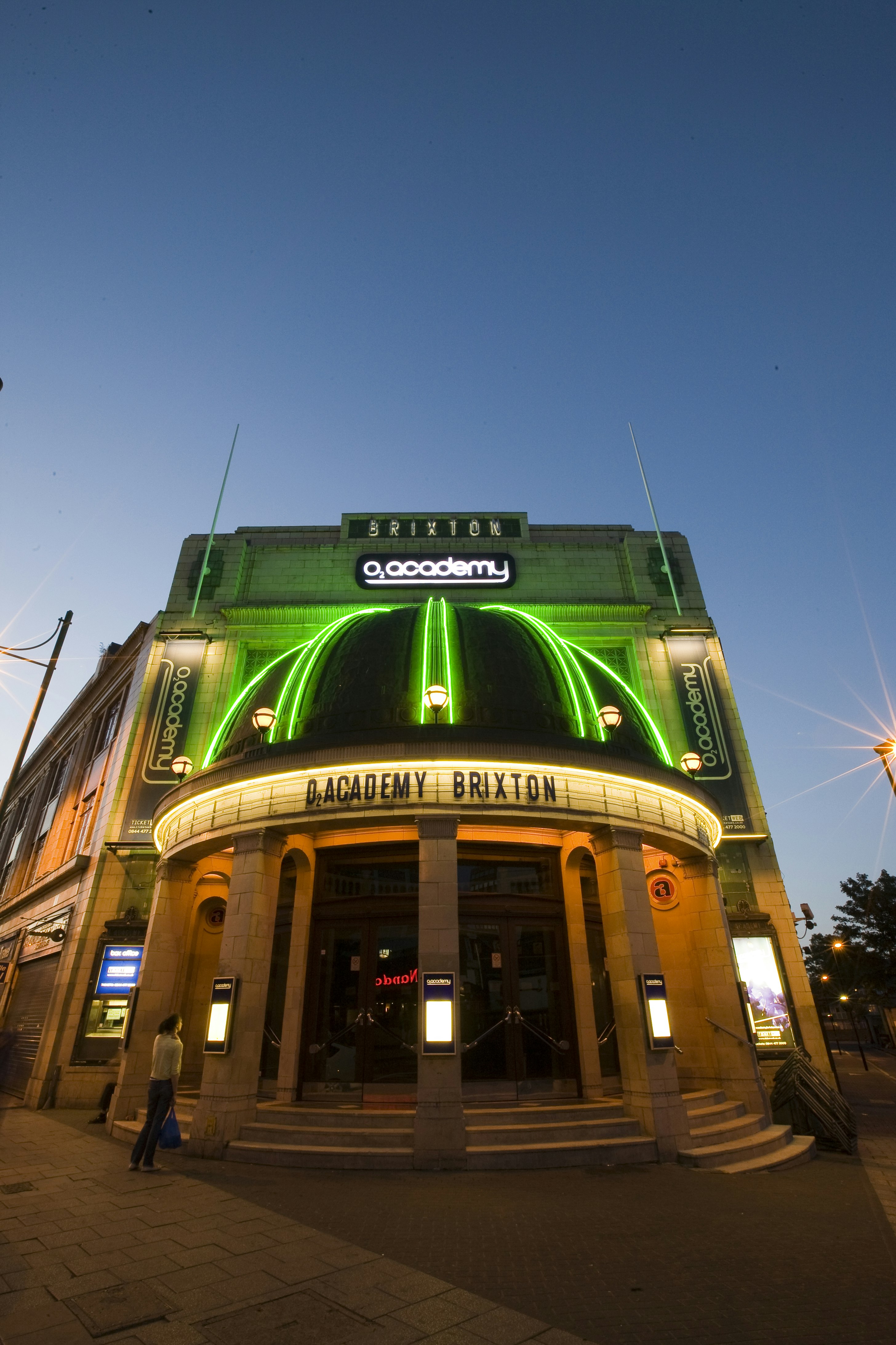 The exterior of O2 Academy Brixton at night, with a cupola lit up in green.