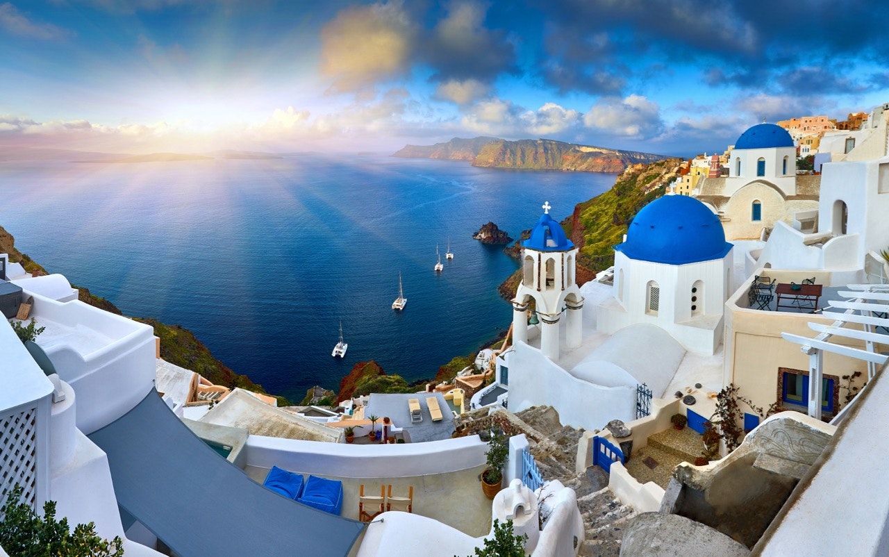 White houses with blue domes around the harbor on Santorini, Greece, at sunrise 