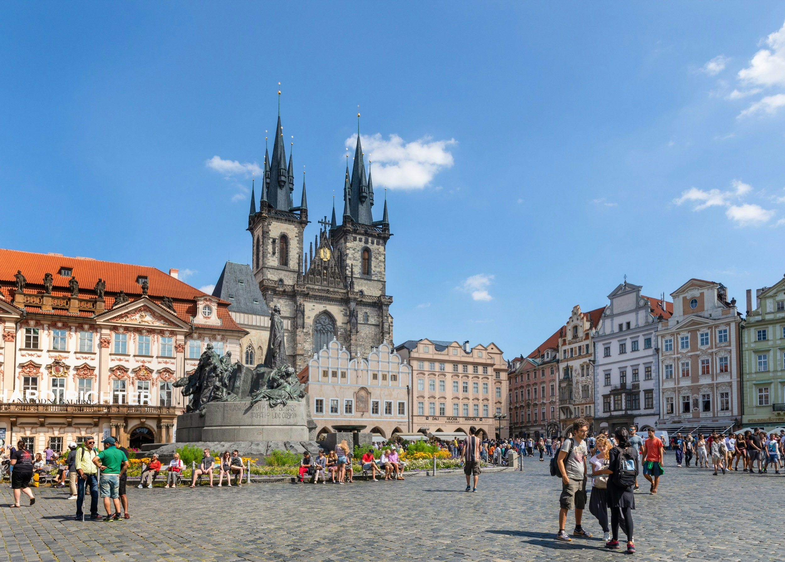 A large group of people gather around the Jan Hus Memorial in Old Town Square in Prague