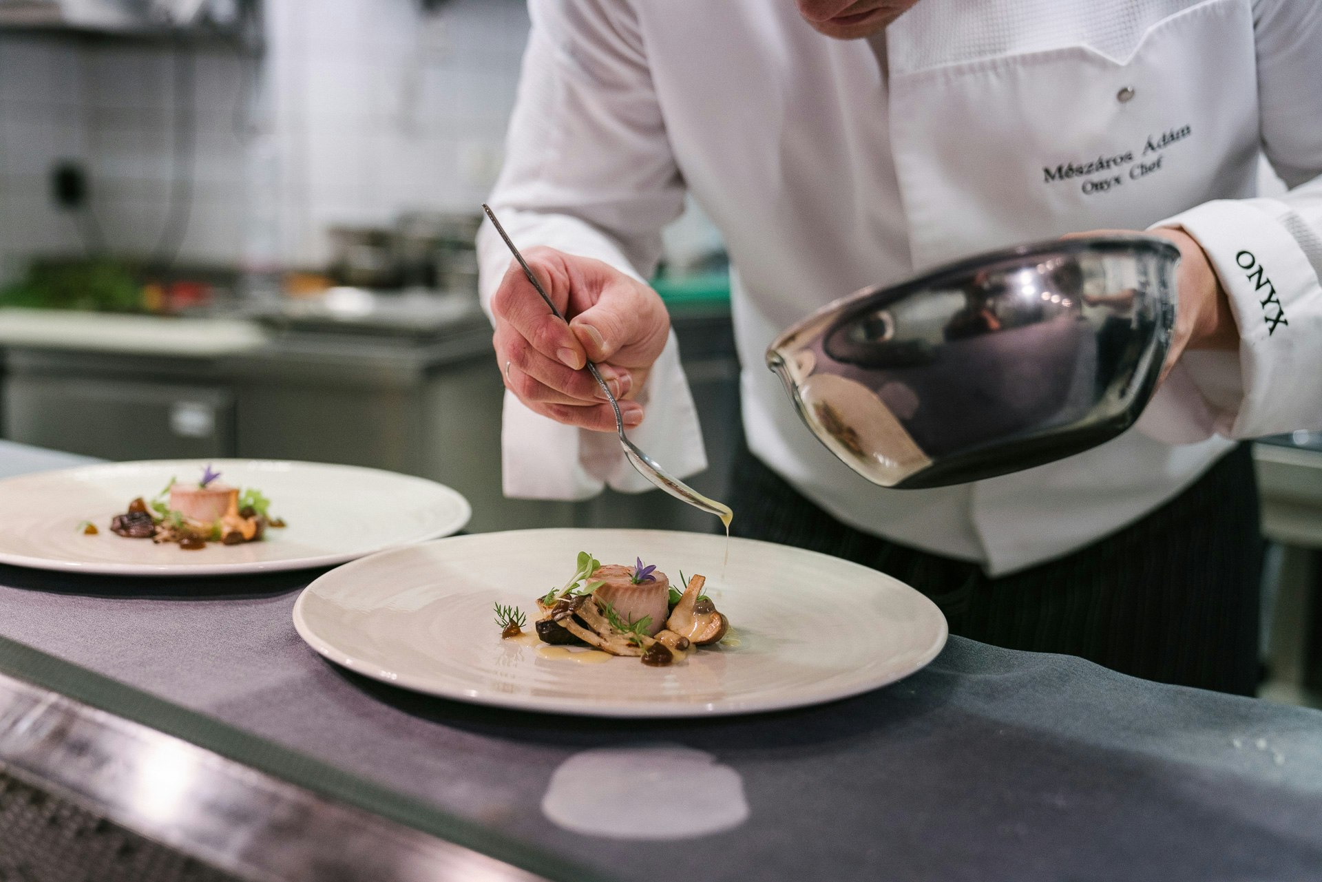 A chef at Onyx restaurant in Budapest, Hungary, is delicately spooning sauce over an exquisitely presented dish.