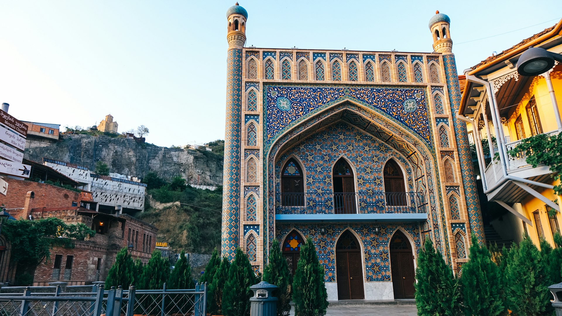 The ornate facade of the Chreli Abano (Orbeliani) sulphur baths in Tbilisi; it's entirely covered in blue and yellow tiles and there are arched doors, as well as minarets on each corner.