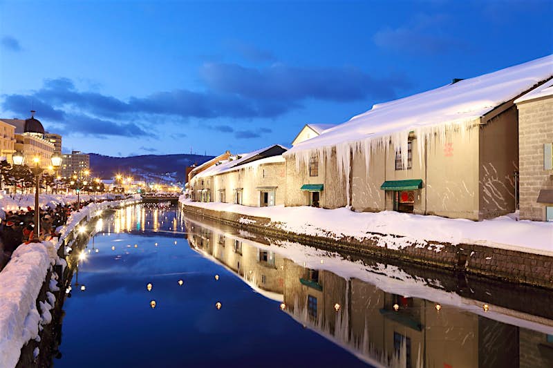 Otaru The illuminated canal of Otaru, Hokkaido, lined with snow-covered buildings, some of which are grand and imposing, at dusk.