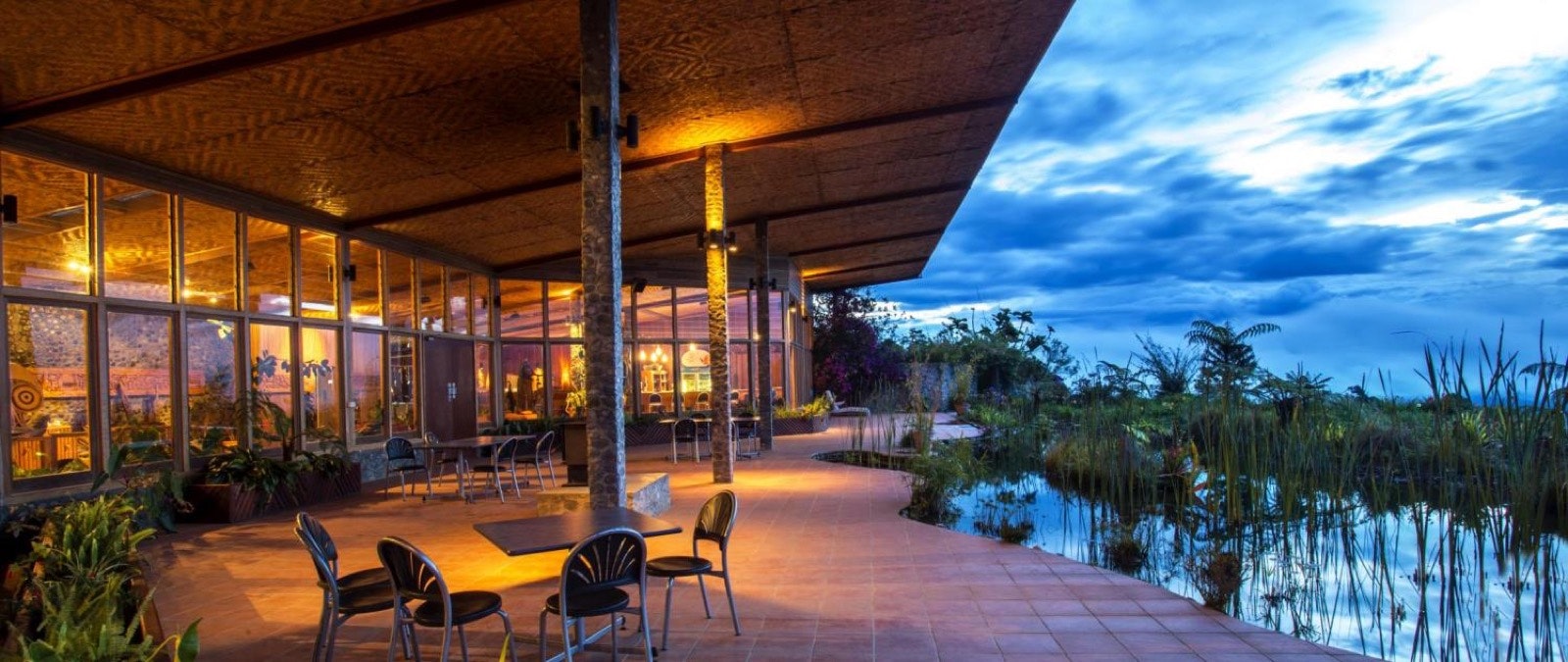 Tables and chairs are arrange around the courtyard overlooking a body of water filled with greenery; eco luxury resorts