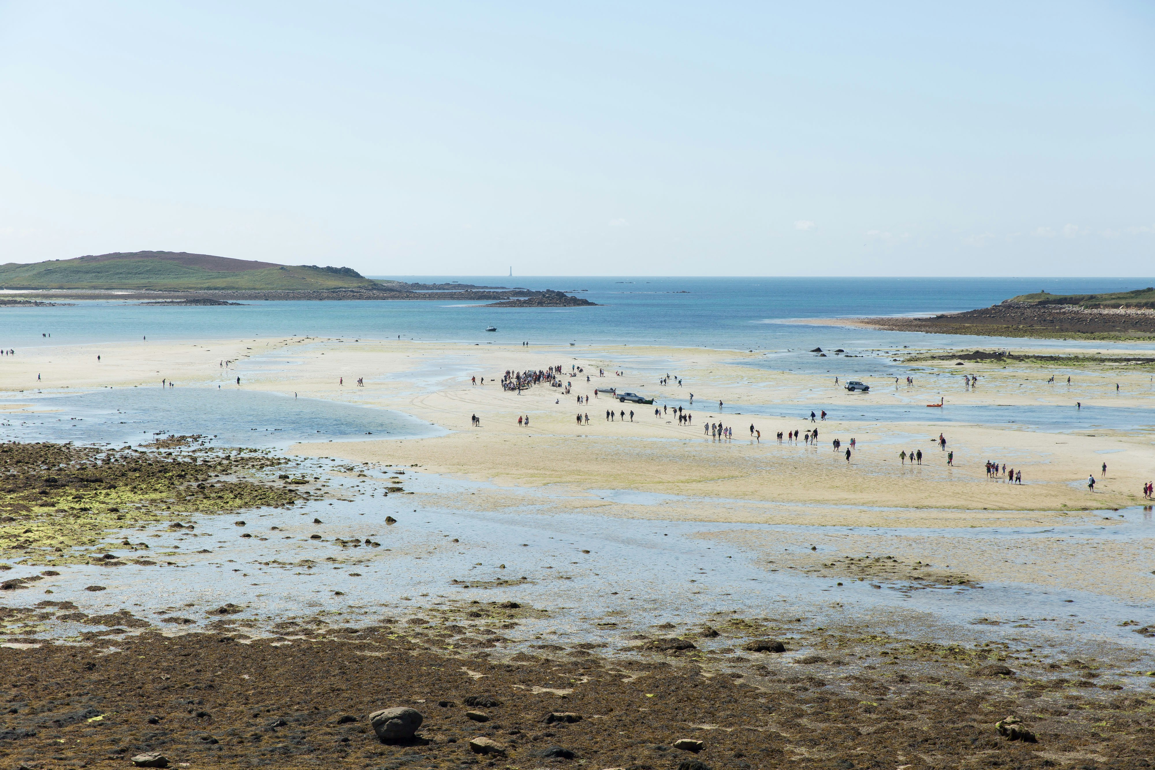 A group of people walk along a low tide.