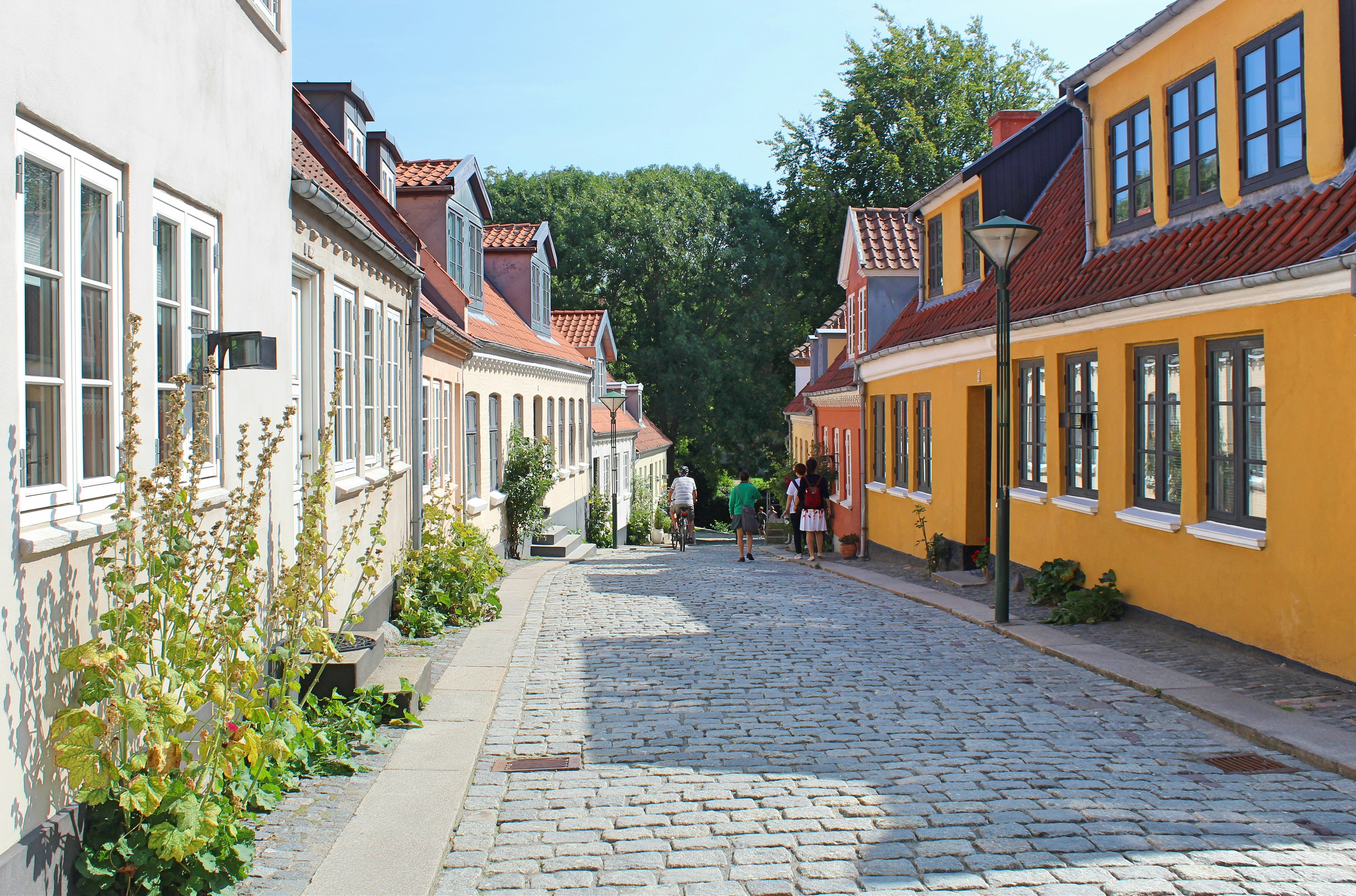 A view of Paaskestræde in Odense, Denmark, an idyllic, cobblestone street lined with colourful houses.