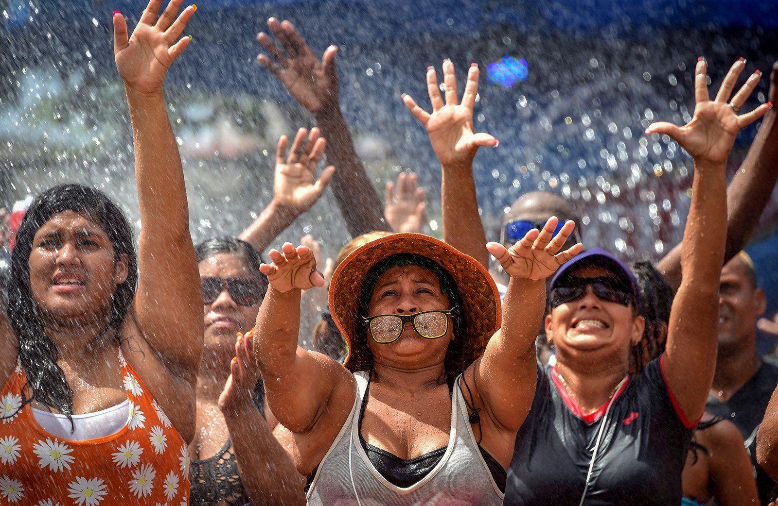 A group of women with their hands in the air get showered with water