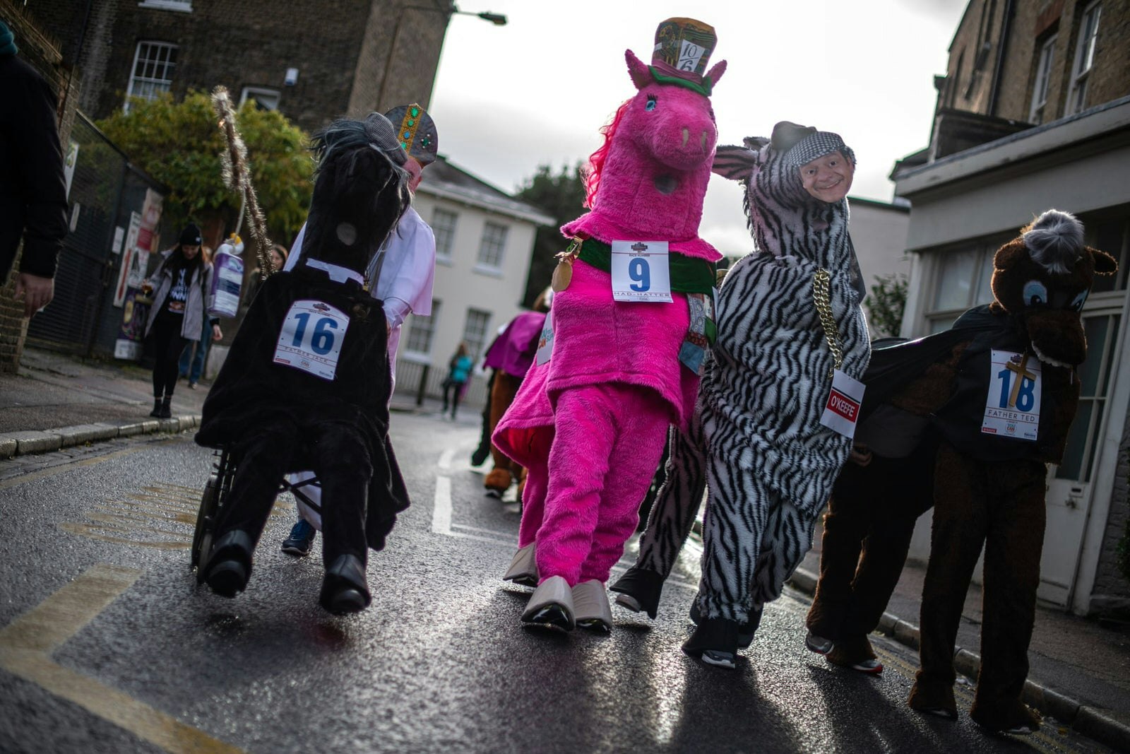 Four pantomime horses walking up a road in London. They are vaguely 'Only Fools and Horses' themed, with one zebra-patterned horse sporting a Del Boy mask.