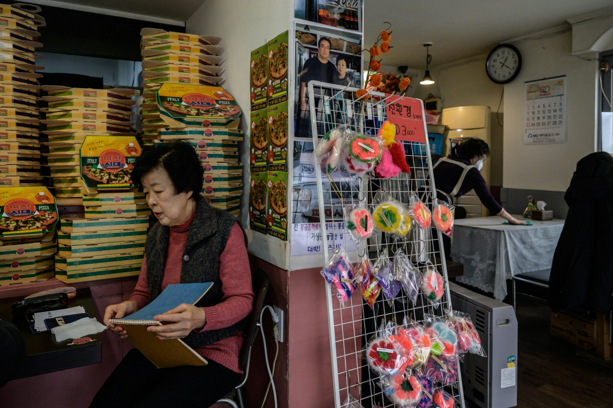 Pizza restaurant owner Eom Hang-ki sits before a photo of her with film director Bong Joon-ho in her restaurant 'Sky Pizza' in Seoul