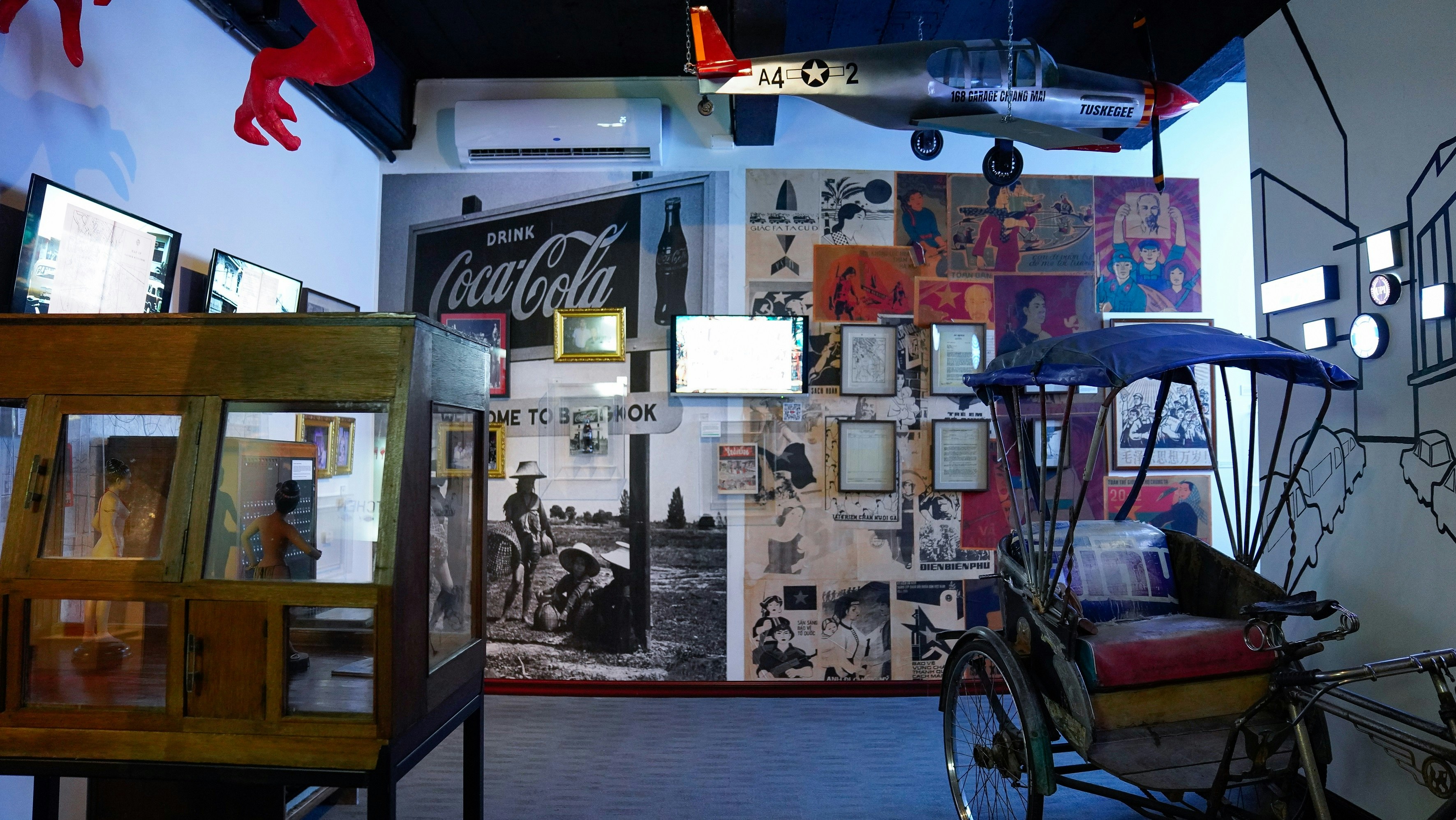 A room from the museum showcasing a number of posters and objects relating to Patpong's early history; including images of rural, farm scenes and an old-looking rickshaw.