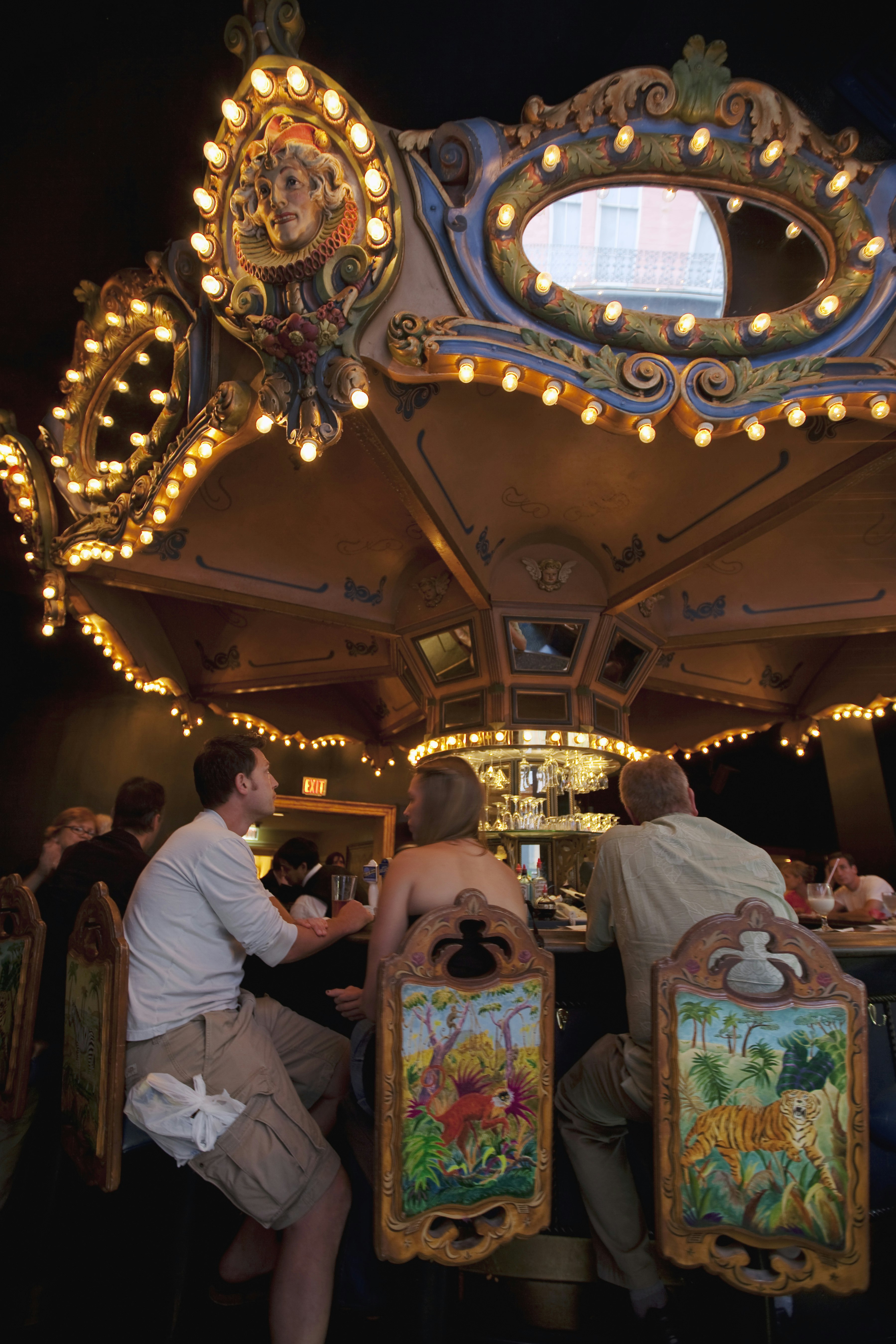 Patrons drinking at the rotating carousel bar, decorated with lights and colorful animals