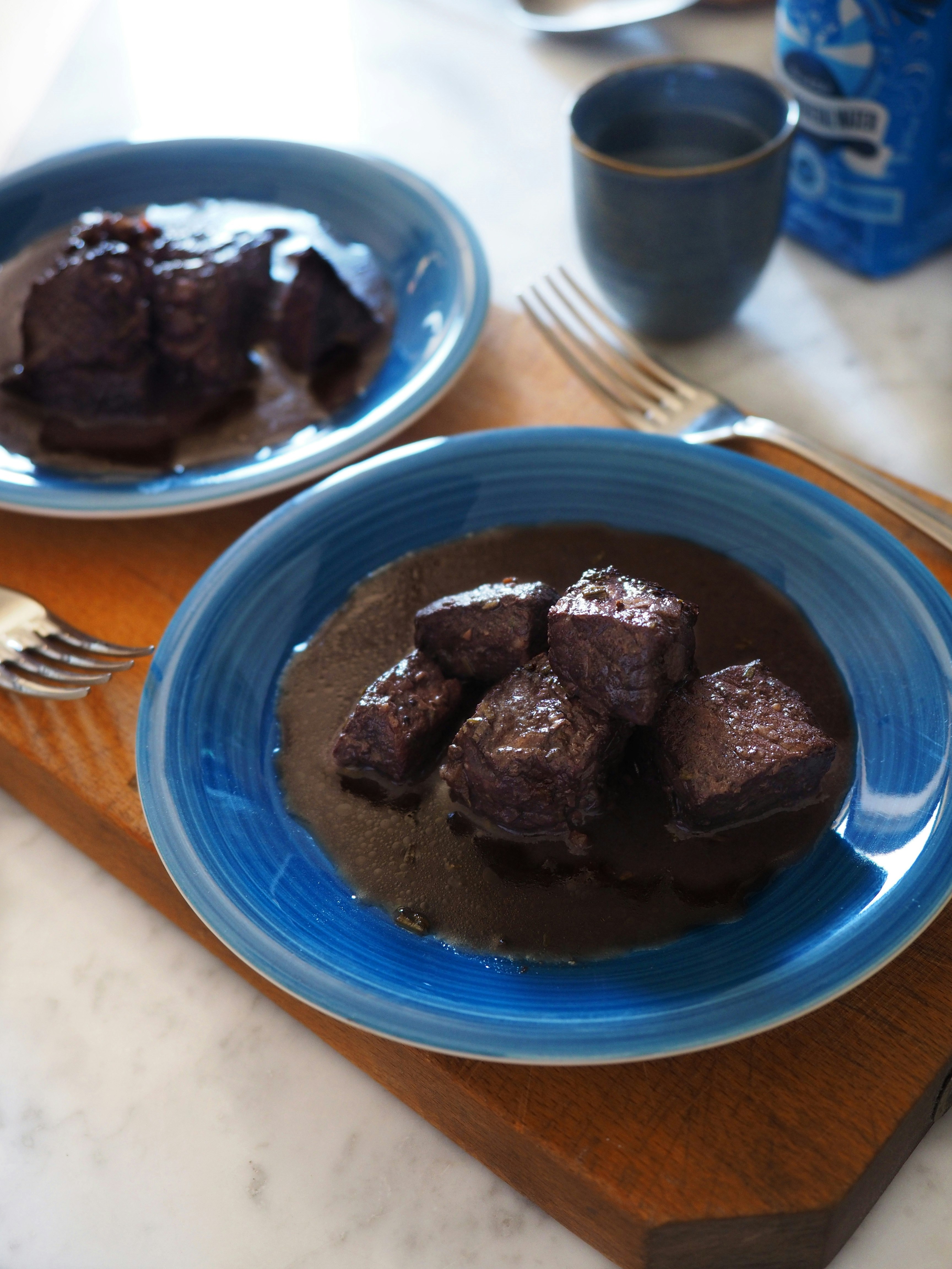 Two bowls filled with peposo, beef and wine stew, a Slow Food dish in Italy