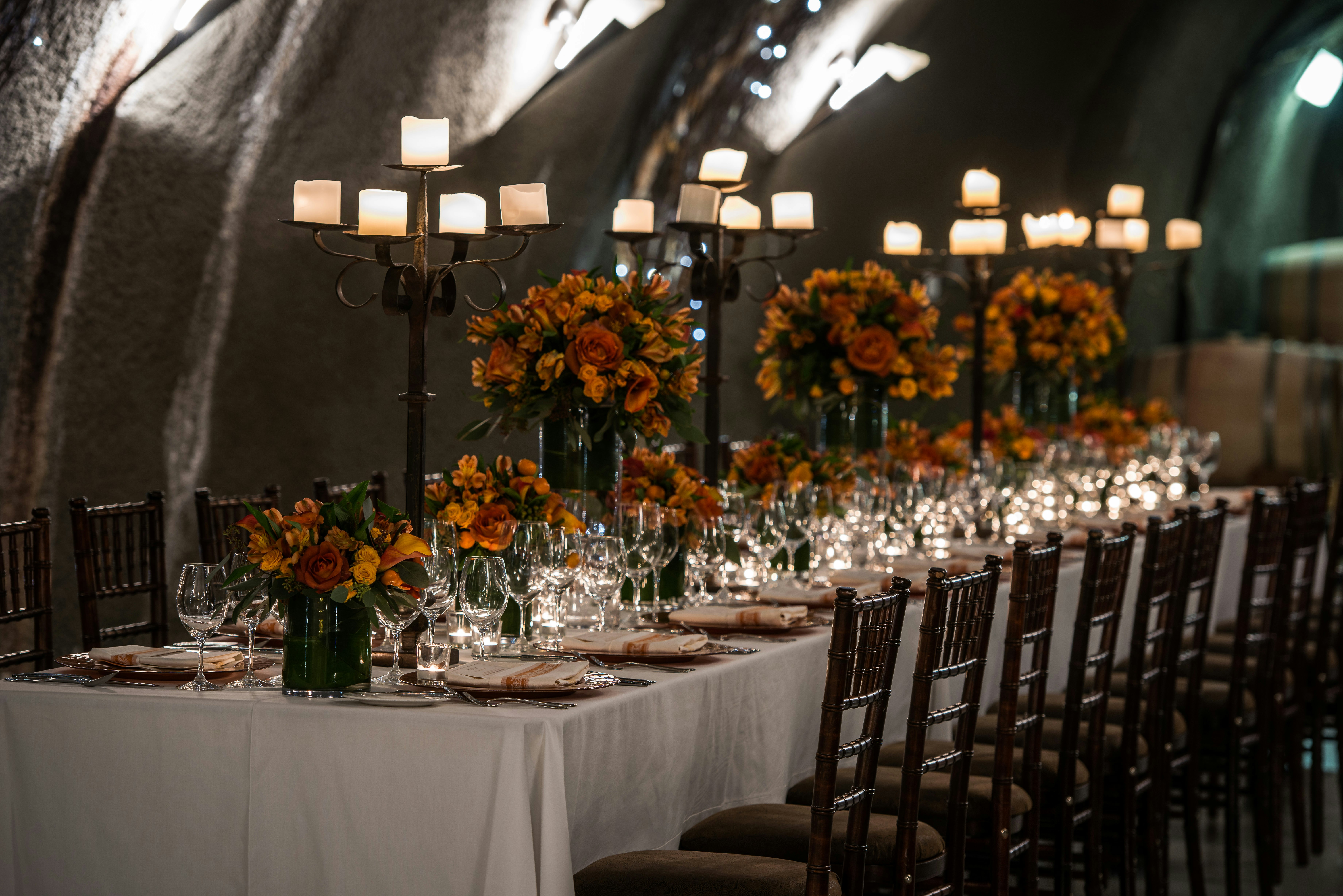 A long table set with candelabra an orange flowers is prepared for an elegant meal 