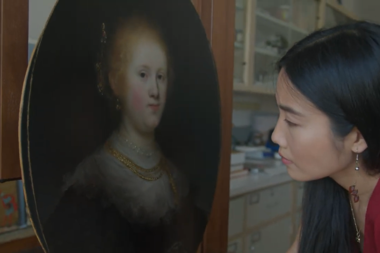 A woman looking at the painting Portrait of a Young Woman
