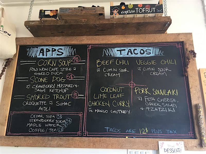 A large chalkboard menu hangs on a wall at Pow Wow Café; Indigenous food 