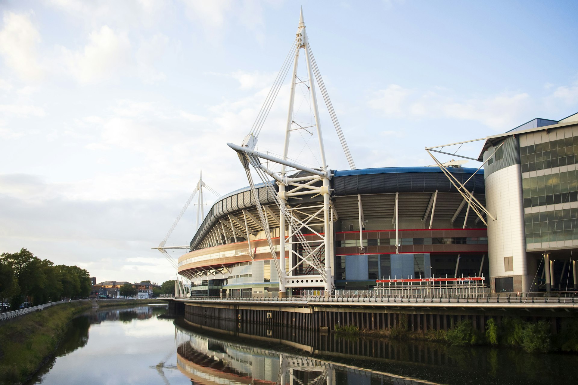 A view of the Principality Stadium in Cardiff, beside the River Taff. The large circular structure is reflected in the calm waters of the river.