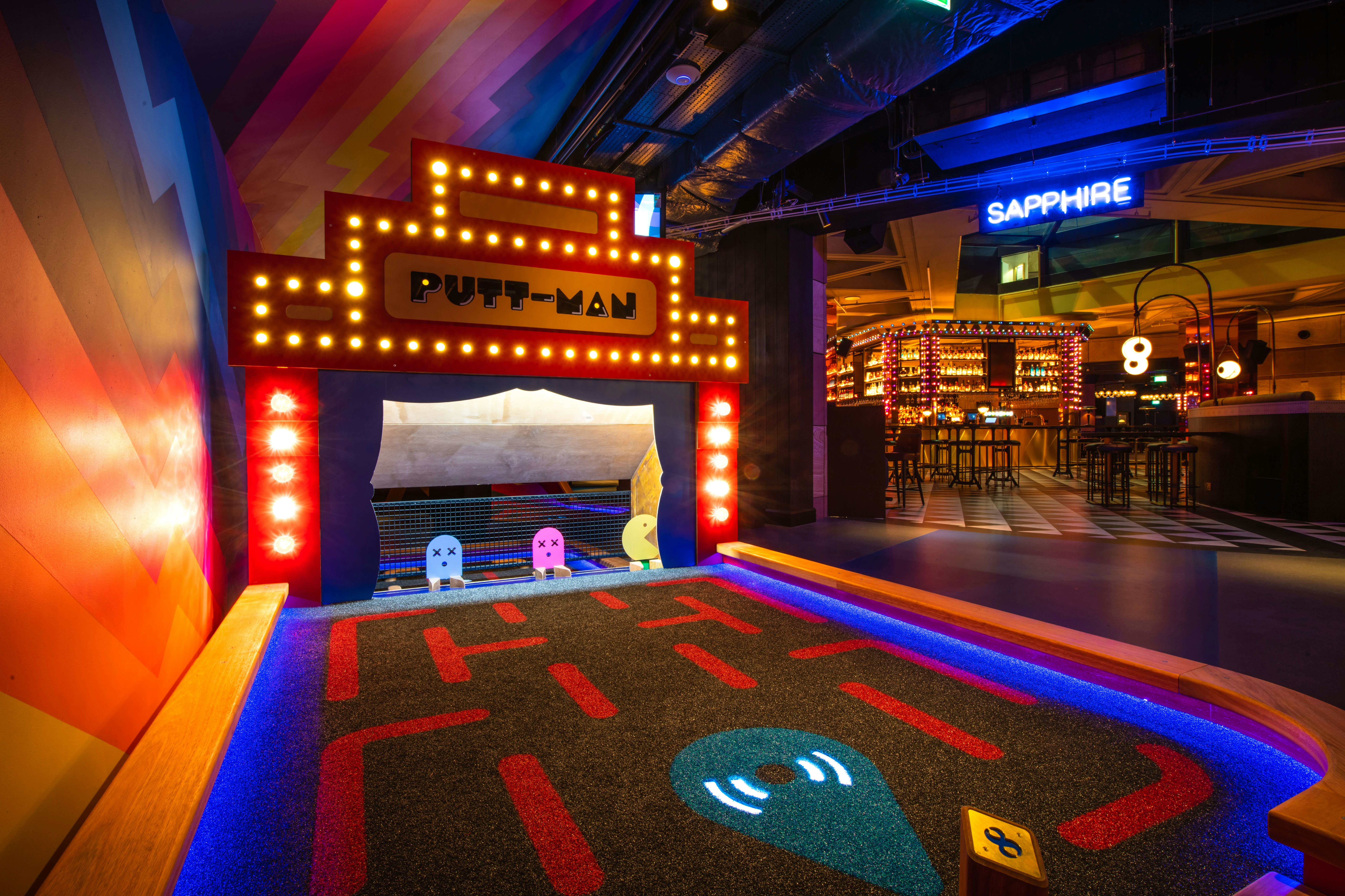 A colorful bar and Pac-Man putting green called Putt-Man at the Puttshack Bank location