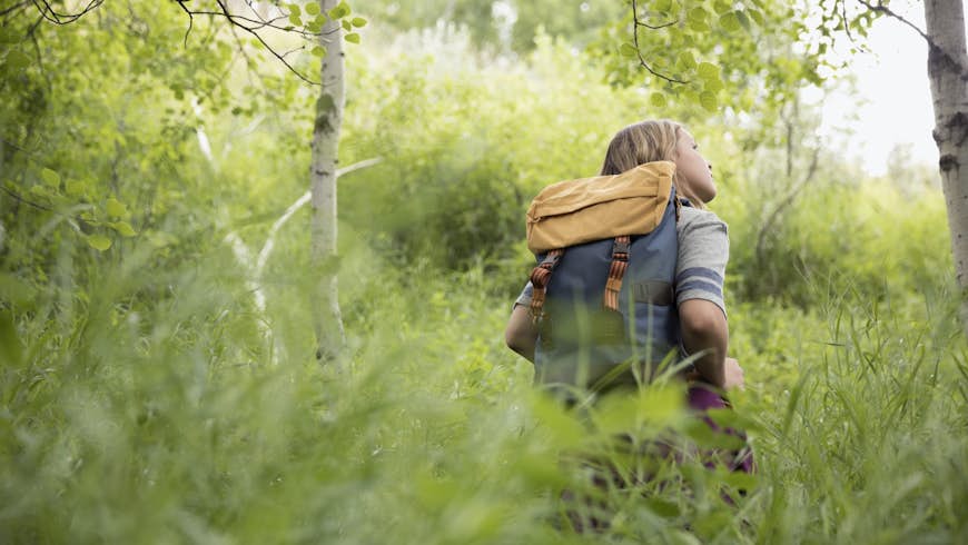 A young woman with a back pack listens to the forest around her; Quiet parks