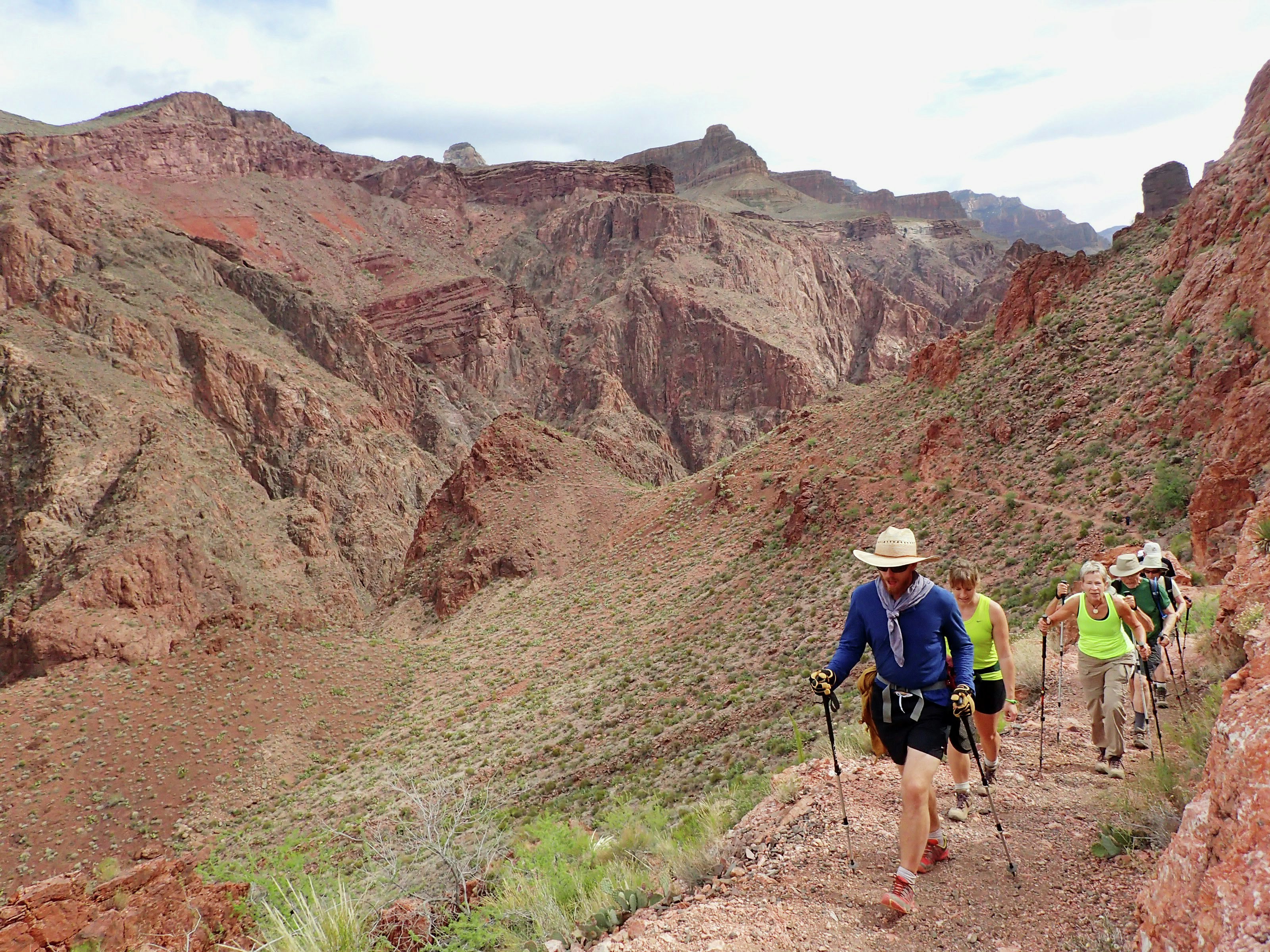 A group of people in hiking gear march up the slope of the Grand Canyon