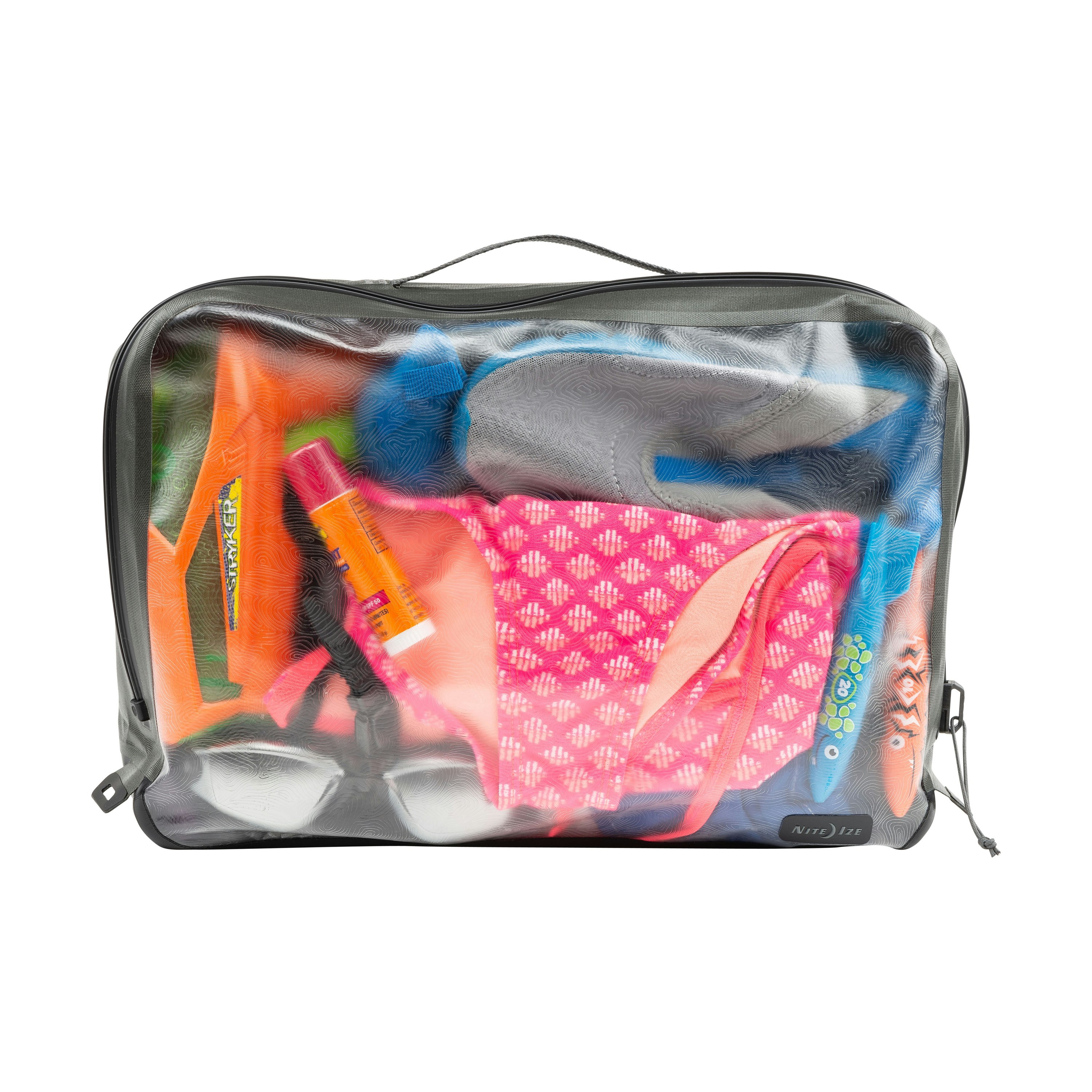 A clear, thick plastic bag with black edges shows the slightly distorted contents of a bright swimsuit in a pink pattern, an orange and pink chapstick, swim goggles, and other aquatic beach gear.