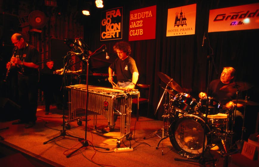 En jazzkvartett bestående av en trummis, pianospelare, klarinettist och en man på xylofon spelar på en svagt upplyst scen på Reduta Jazz Club