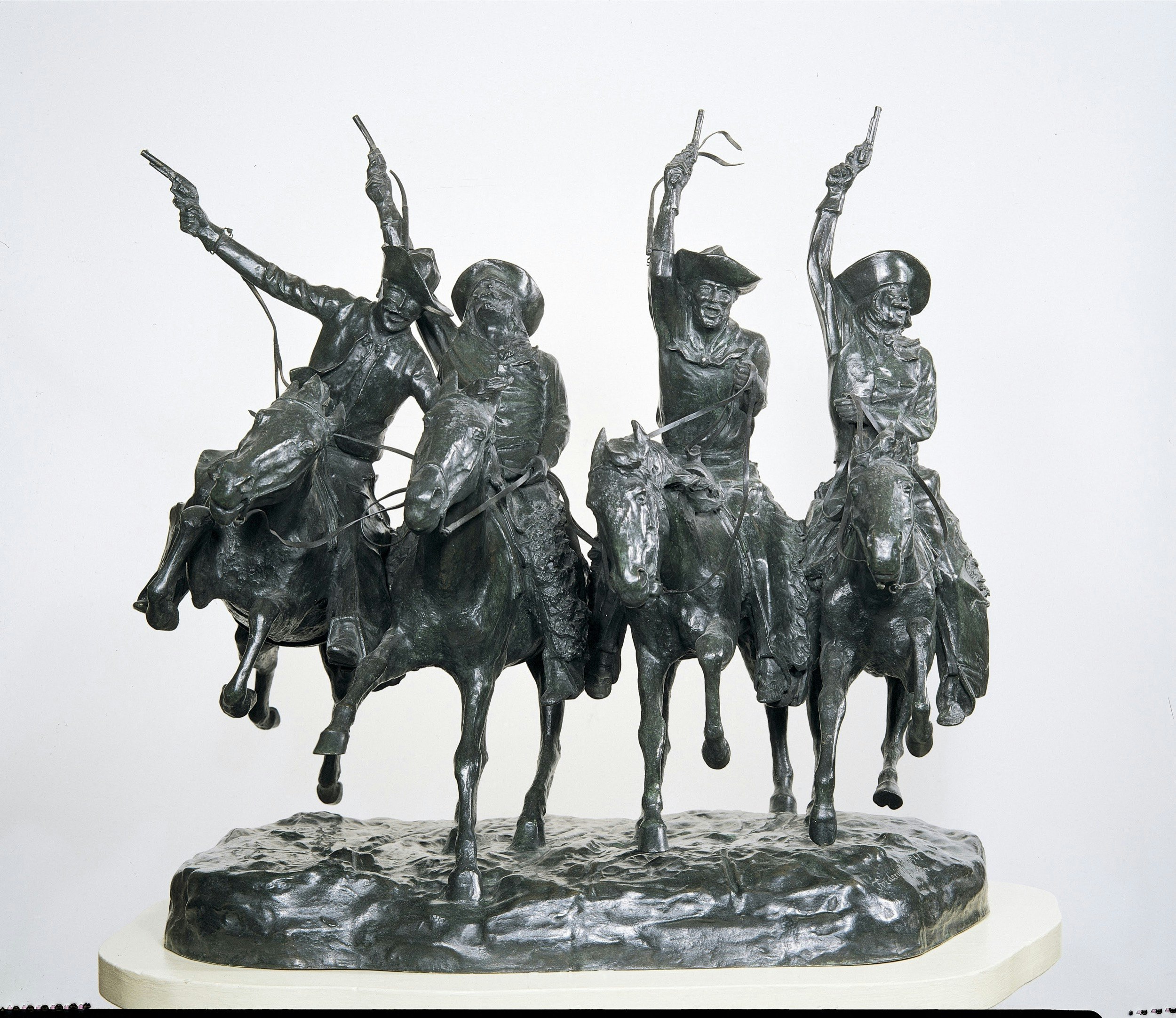A bronze sculpture shows four men on horseback at a fast gallop with their guns in the air; Where to see Remington in America