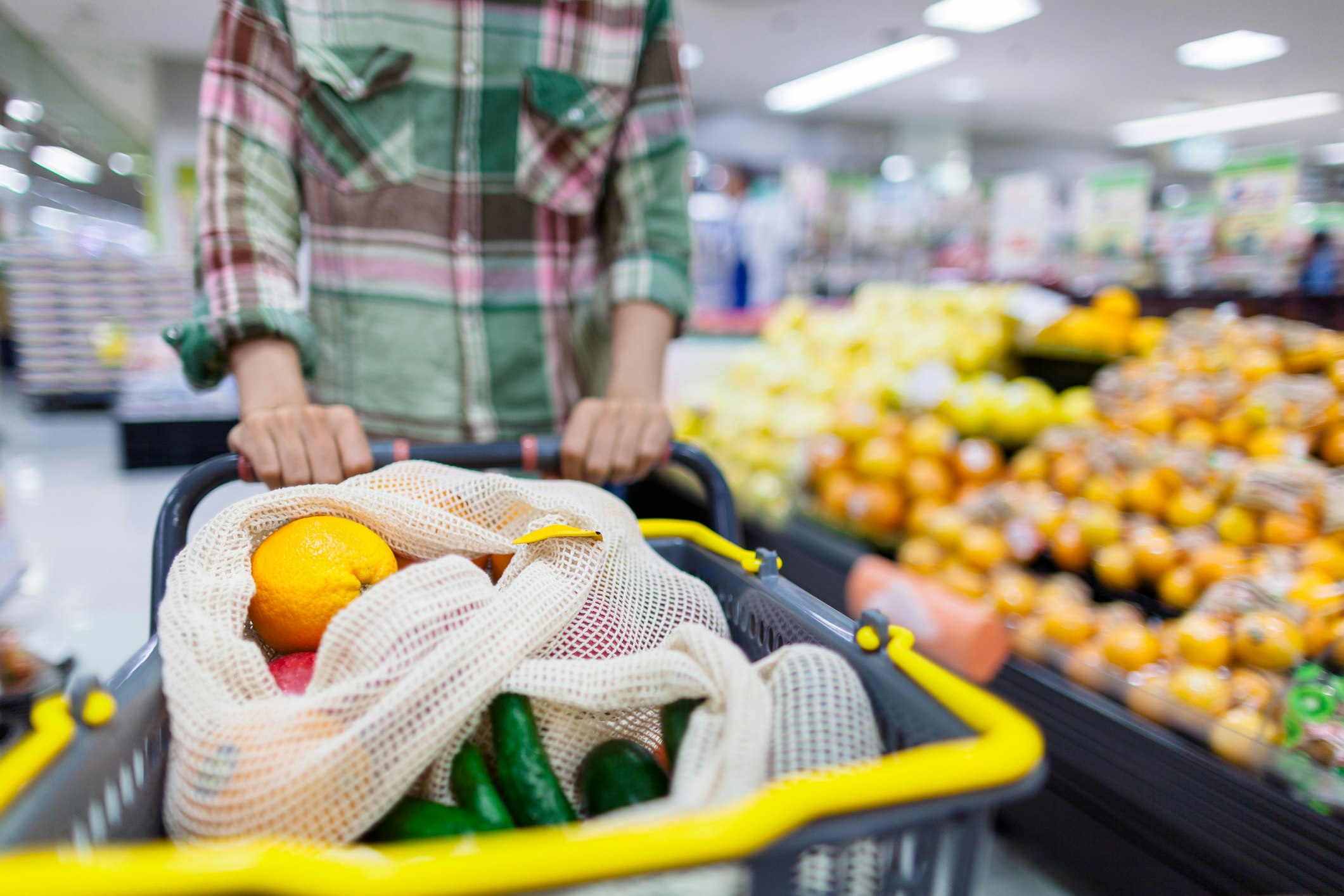 Young man doing shopping at supermarket with reusable shopping bag