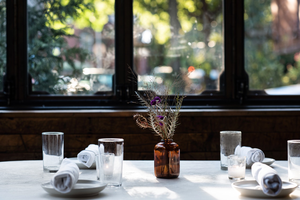 Place settings with a vase at a table by the windows