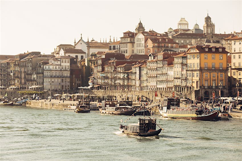 Ribeira-district-porto Shot from a boat in the Douro River, this image shows boats on the river and moored on the bank in Ribiera; this section of town is blanketed in historic, colourful buildings.