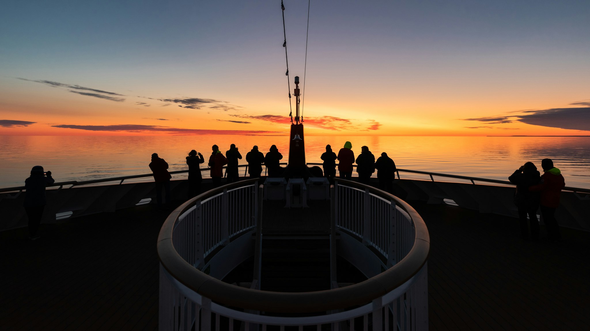 People looking out on the sea at sunset from the Roald Amundsen ship