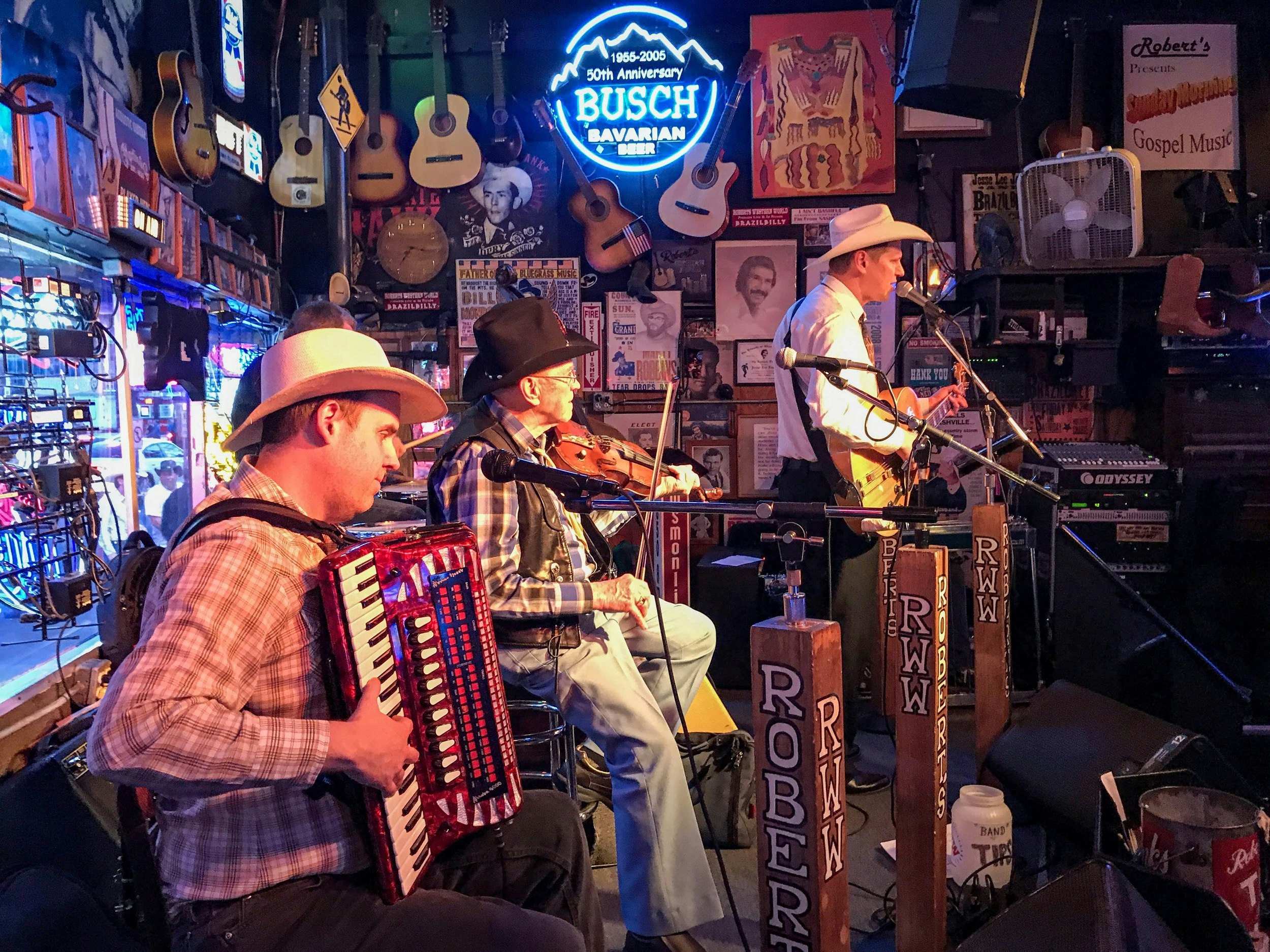 A country band with a fiddle player performs at a honky tonk; Best country music venues in Nashville