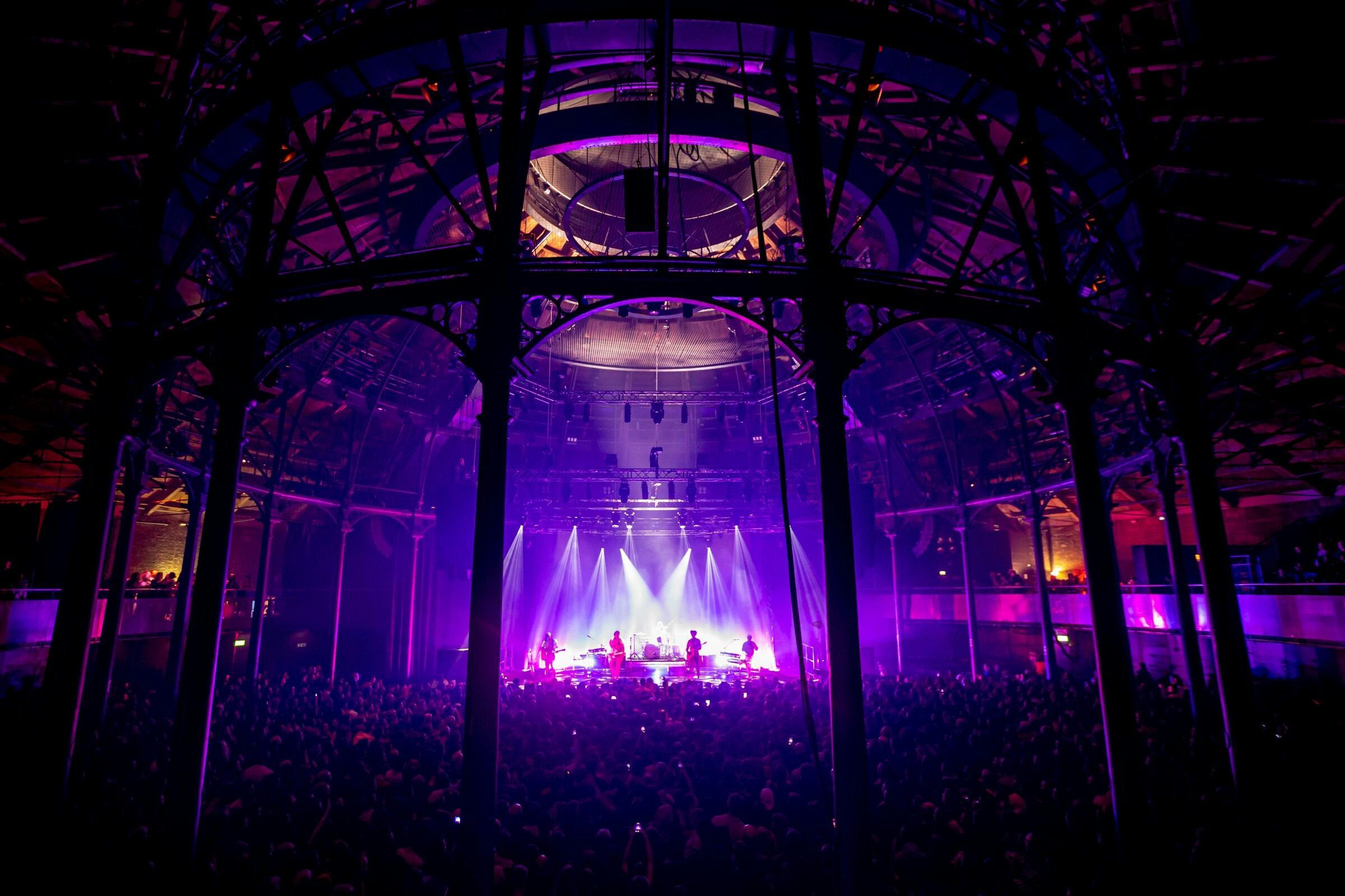 The audience watch a band playing on a lit-up stage at the Roundhouse in London.