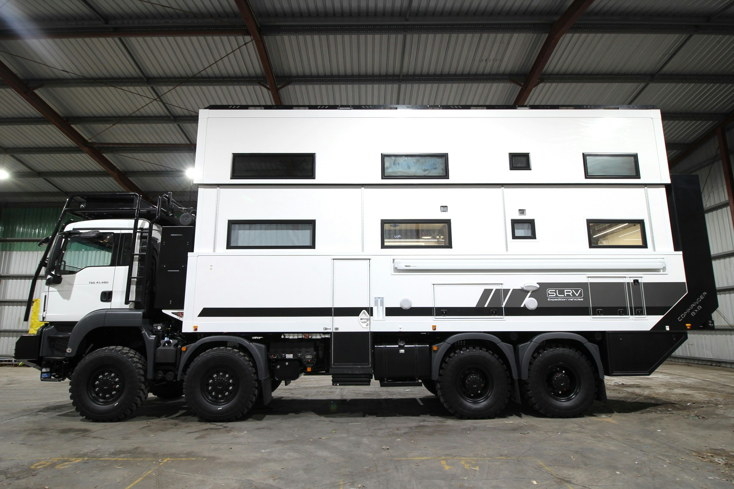 The exterior of a white two-storey expedition vehicle that can sleep up to 10 people