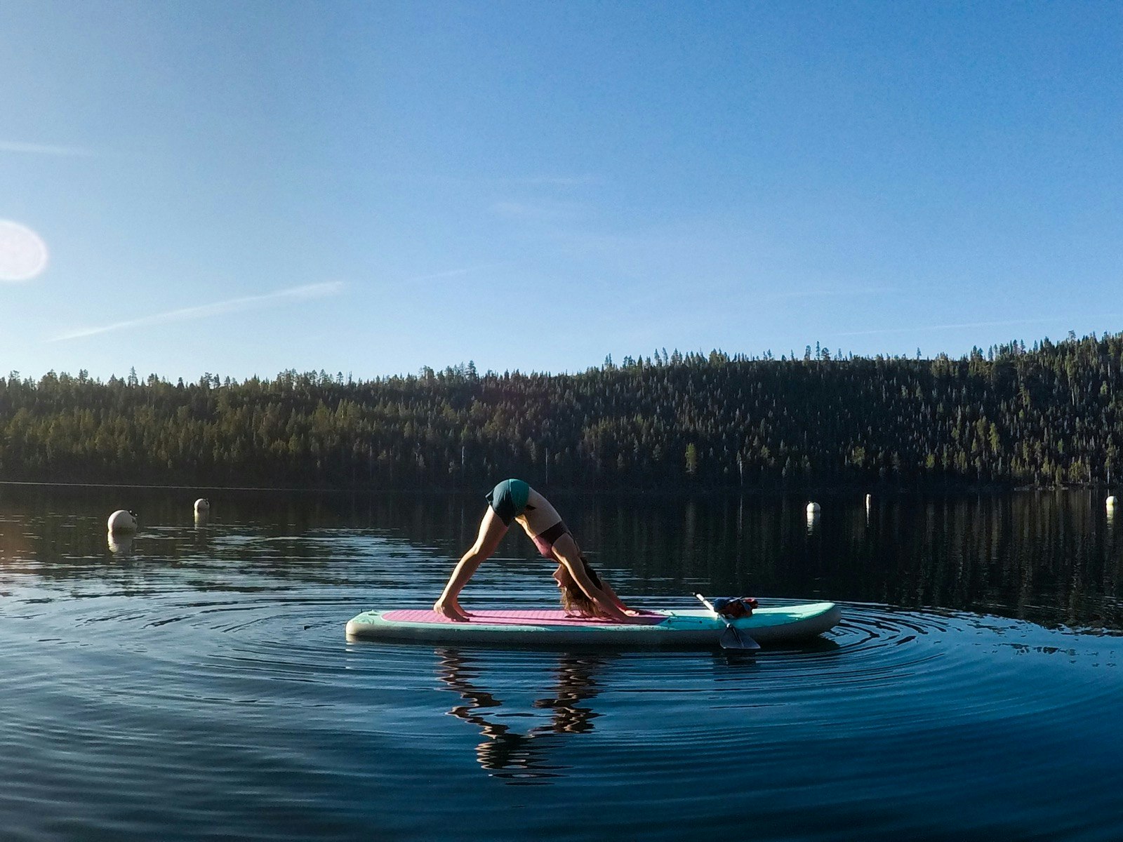 A woman performs the downward facing dog yoga pose on a stand up paddle board in Lake Tahoe