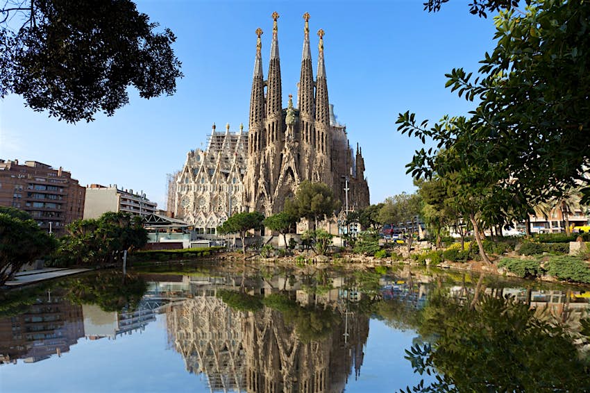 The gothic spires of the Sagrada Familia are reflected in a lake